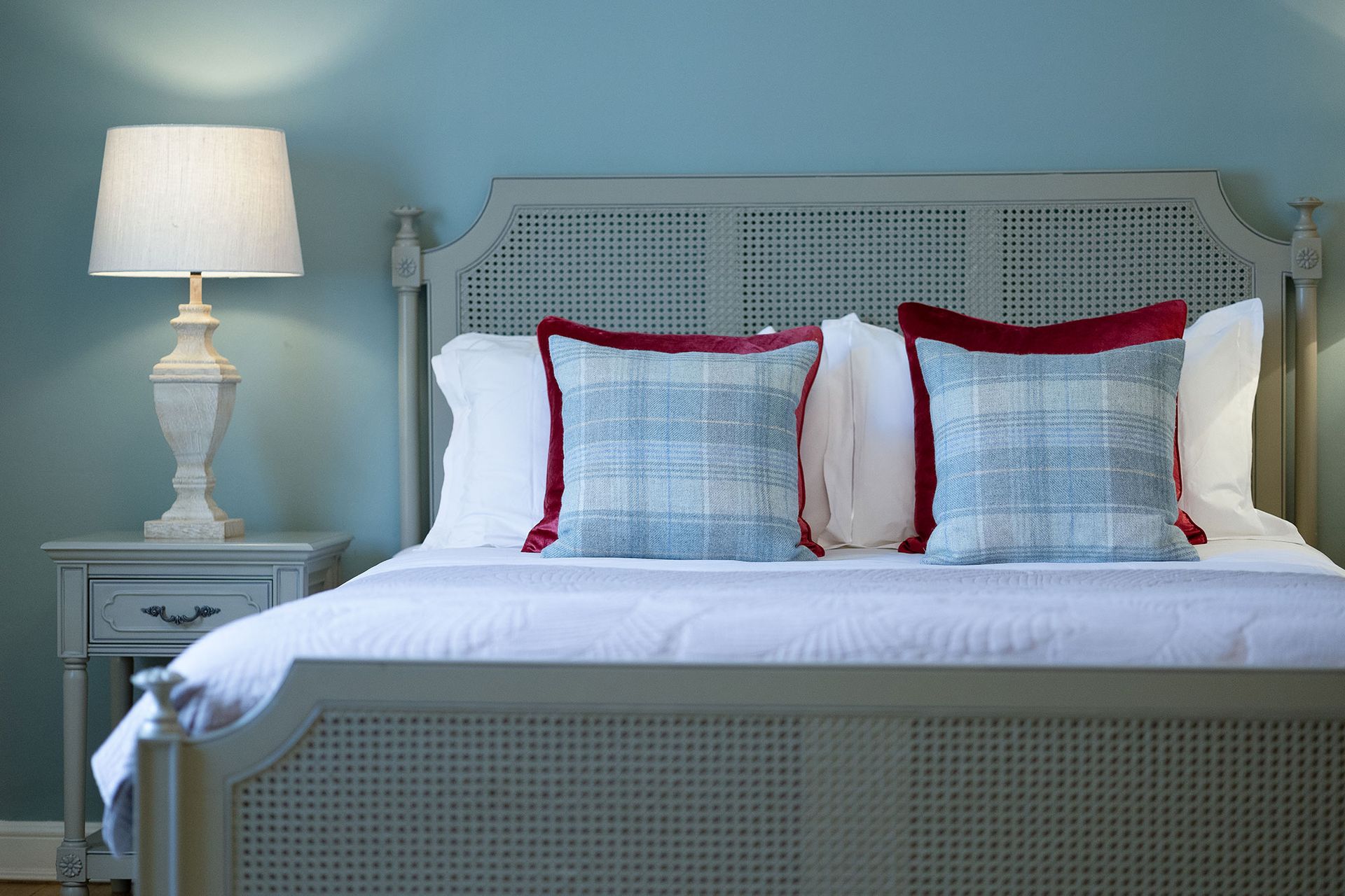 a bedroom with a bed , nightstand , lamp and blue walls .