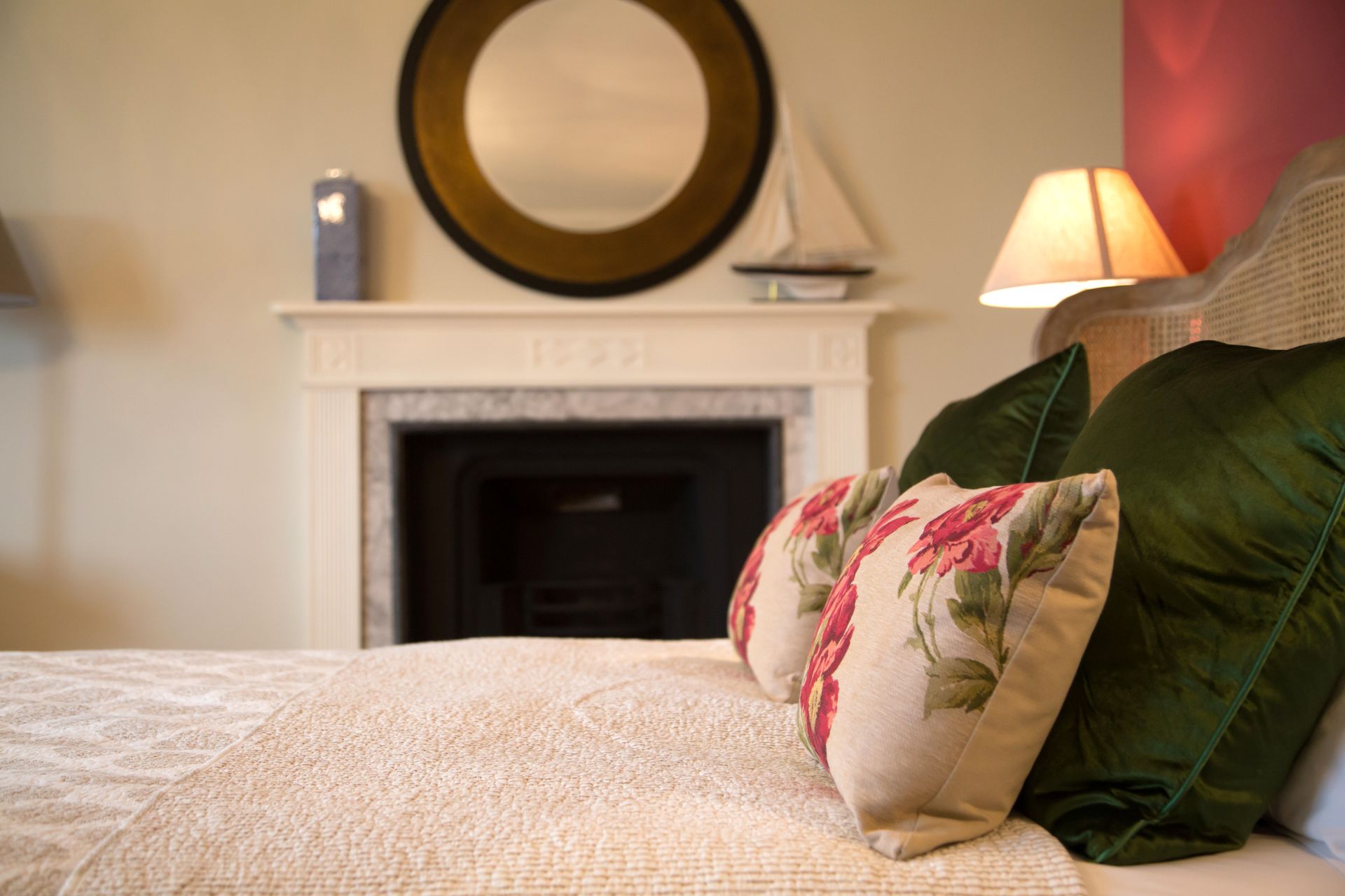 a bed with green pillows and a fireplace in the background