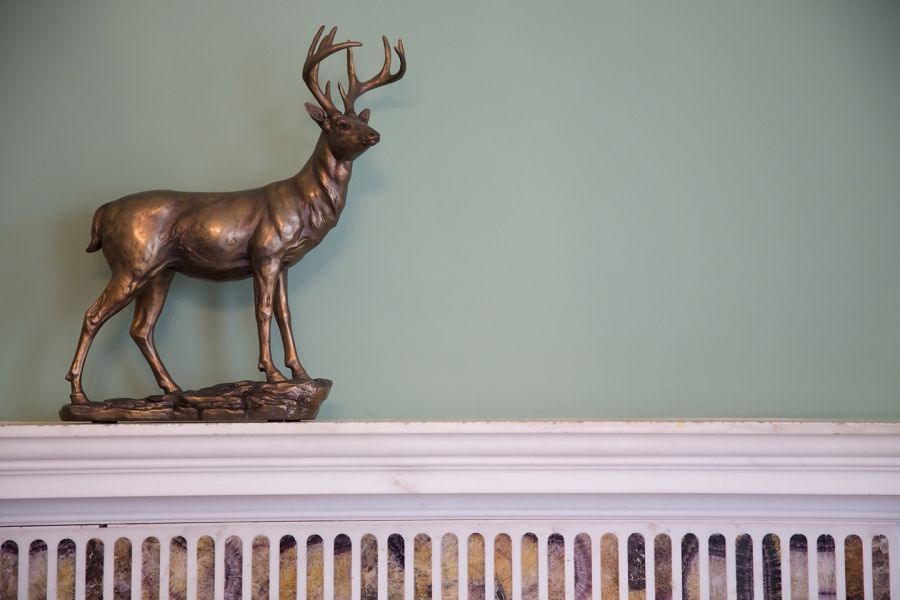 a bronze statue of a deer is sitting on a mantle .