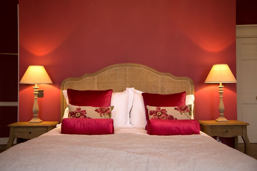 a bedroom with a bed and two lamps and a red wall
