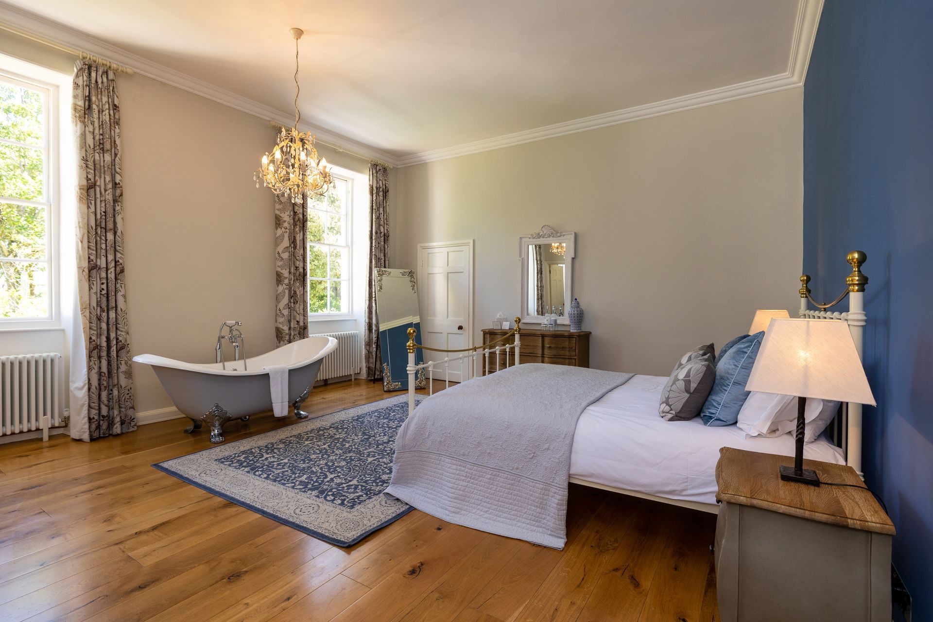 a bedroom with a bed , bathtub , nightstand and chandelier .