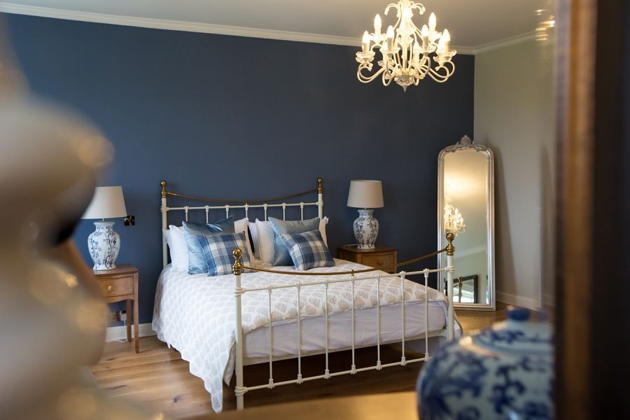 a bedroom with a bed , lamps , a mirror and a chandelier .