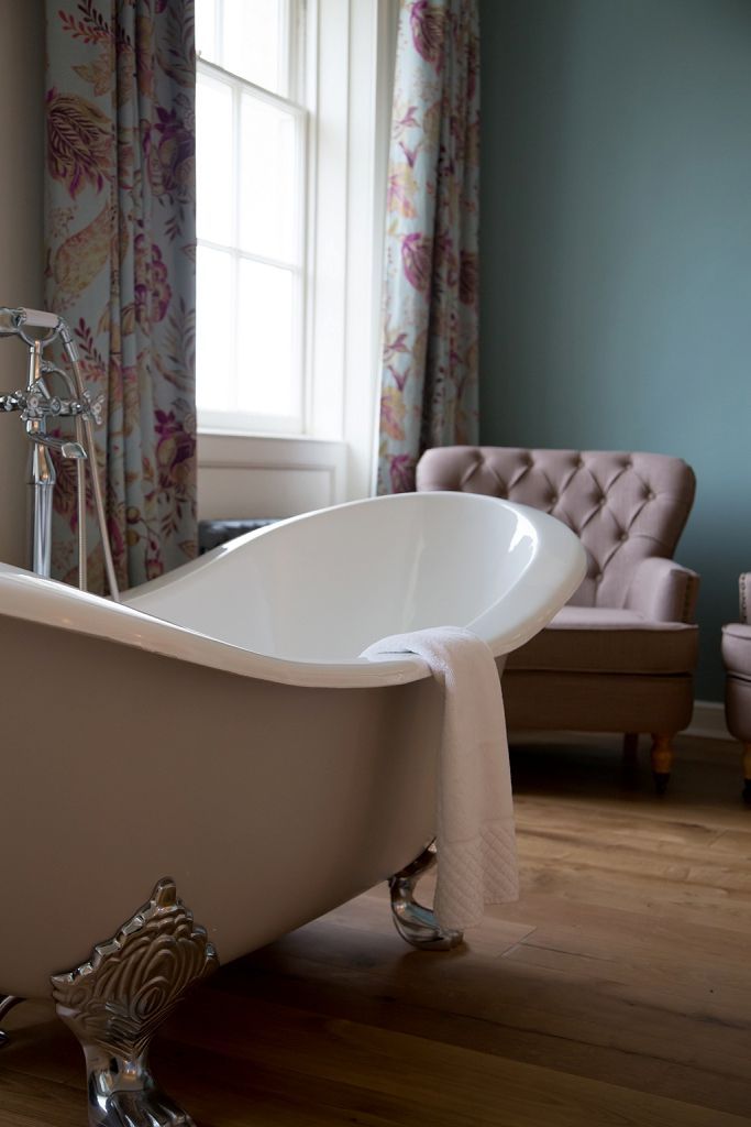 a bathroom with a bathtub , chair and window .