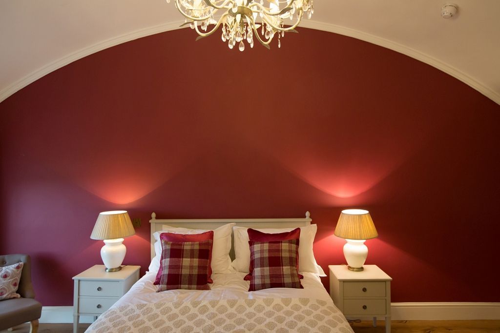 a bedroom with a bed , nightstands , lamps and a chandelier .