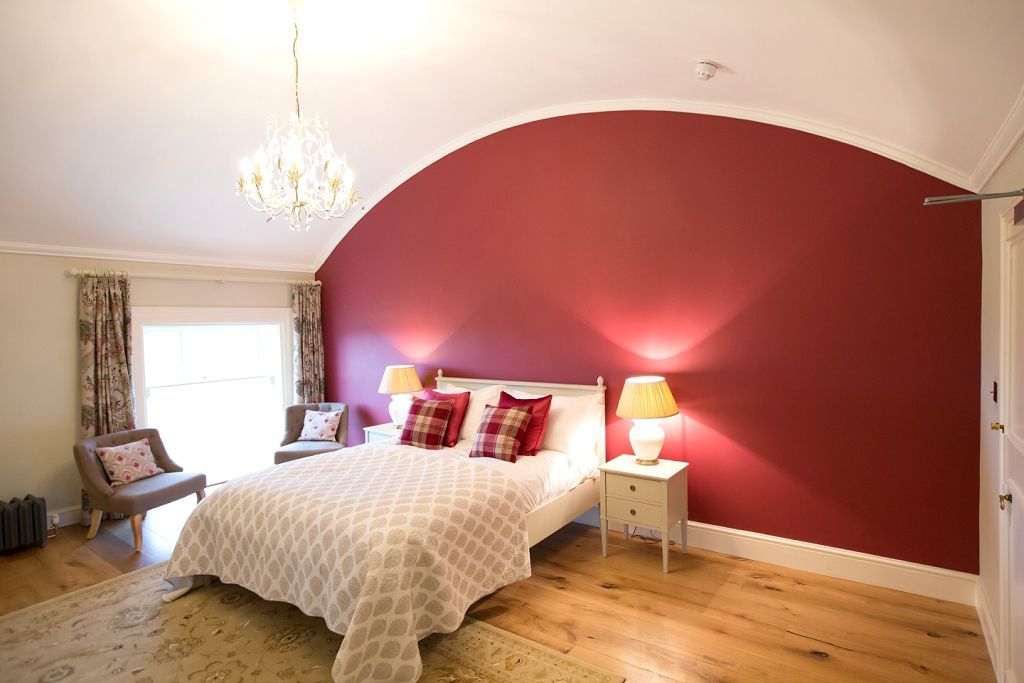 a bedroom with a large bed and a red wall