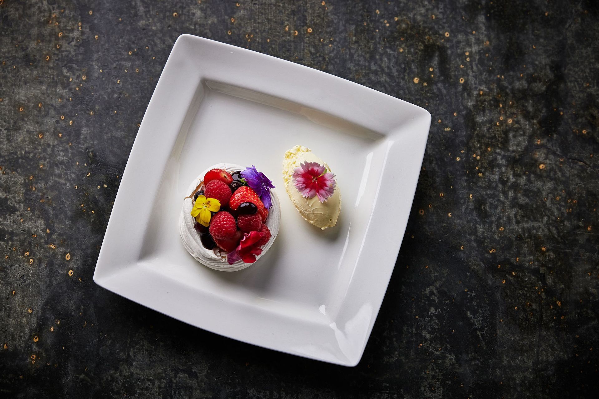 A white plate topped with a dessert and berries on a table.