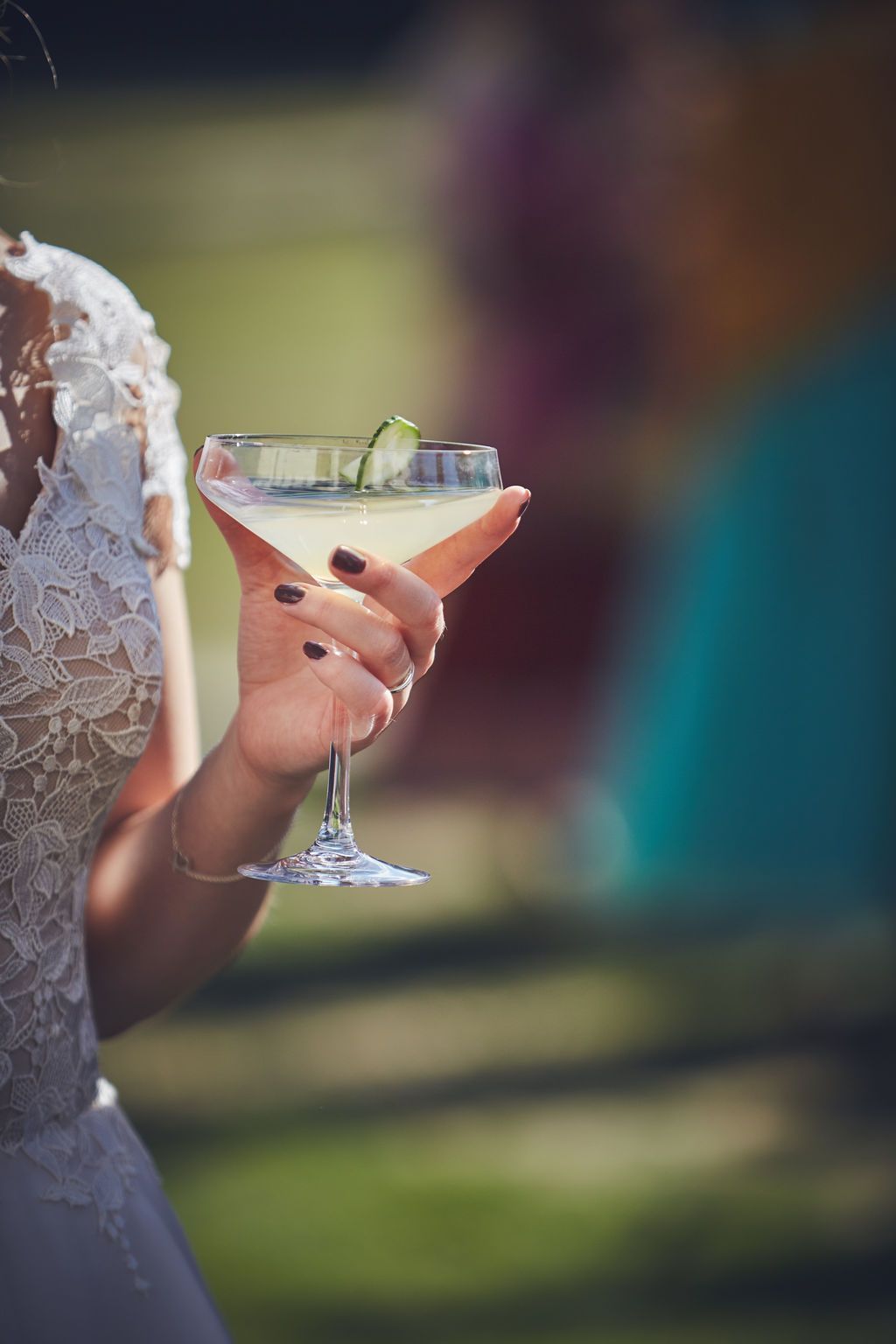 a bride in a wedding dress is holding a martini in her hand .