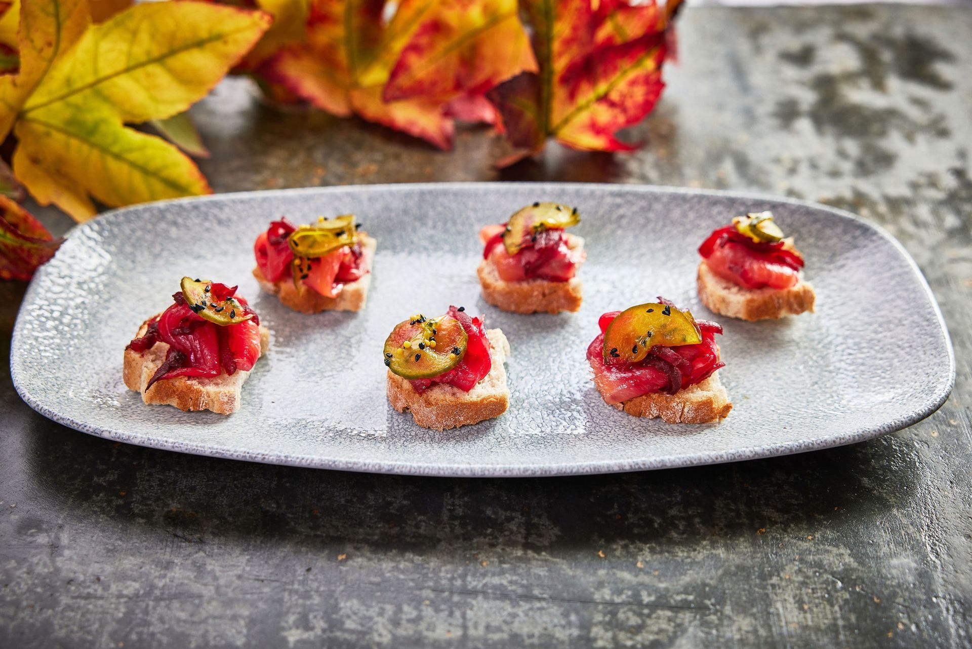 a plate of food on a table with leaves in the background .