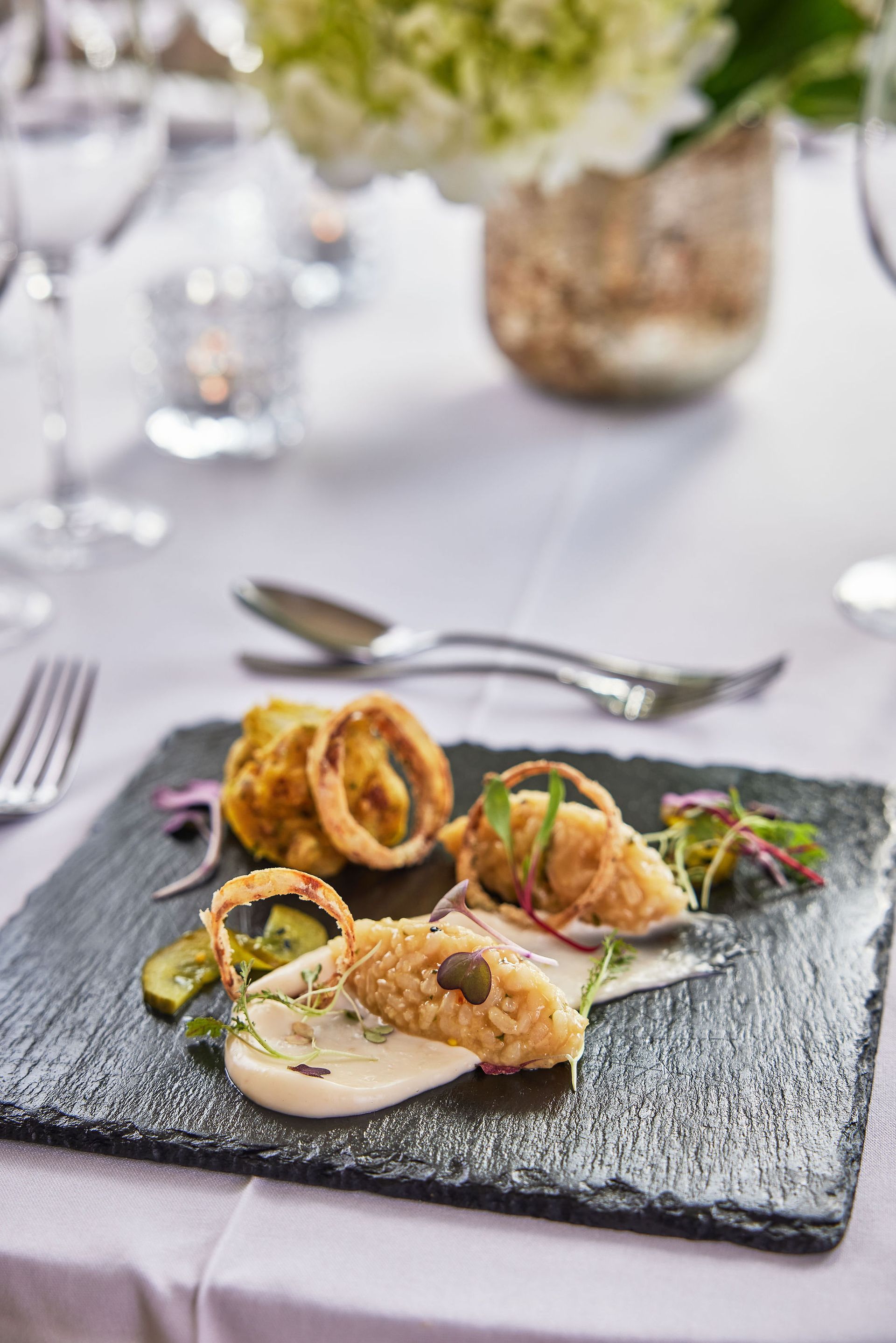 a plate of food on a table with a vase of flowers in the background .