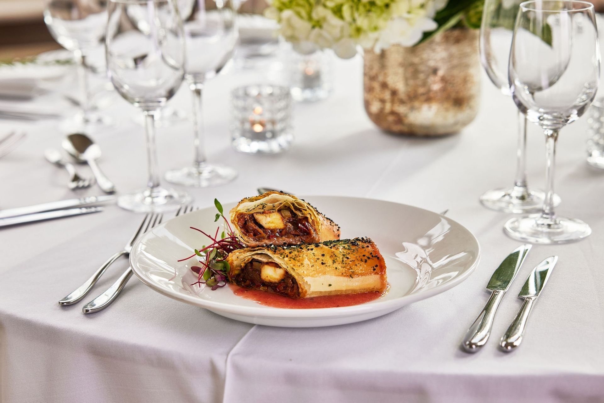 a plate of food is sitting on a table with wine glasses and silverware .