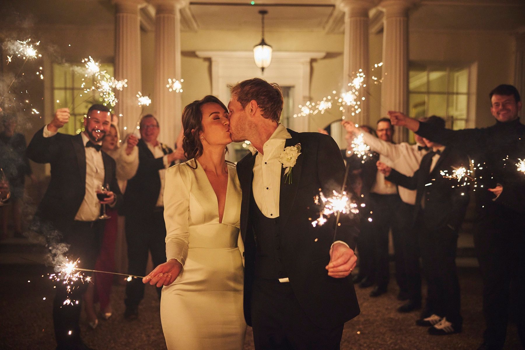 a black and white photo of a bride and groom walking in a field .
