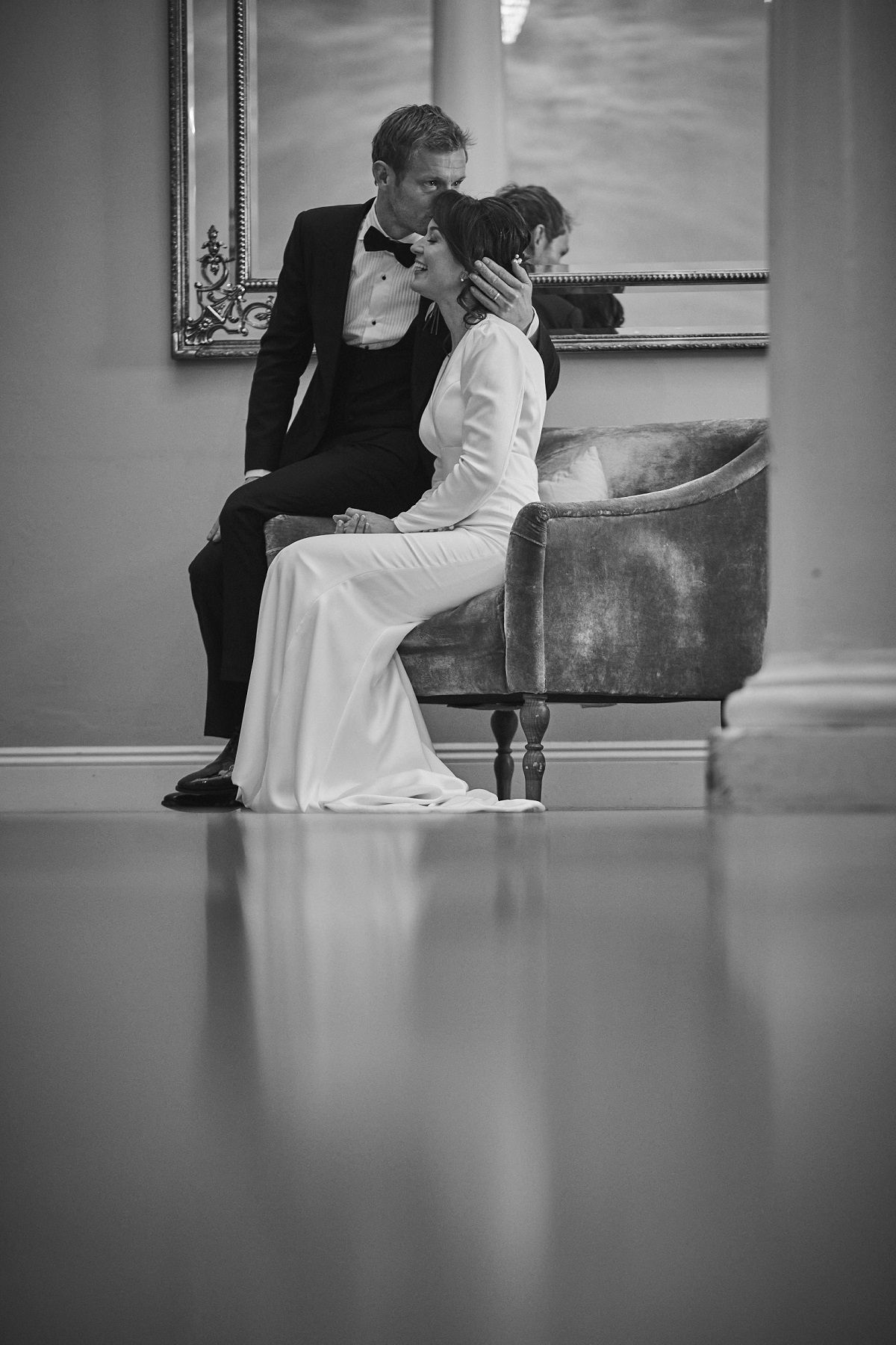 a black and white photo of a bride and groom walking in a field .