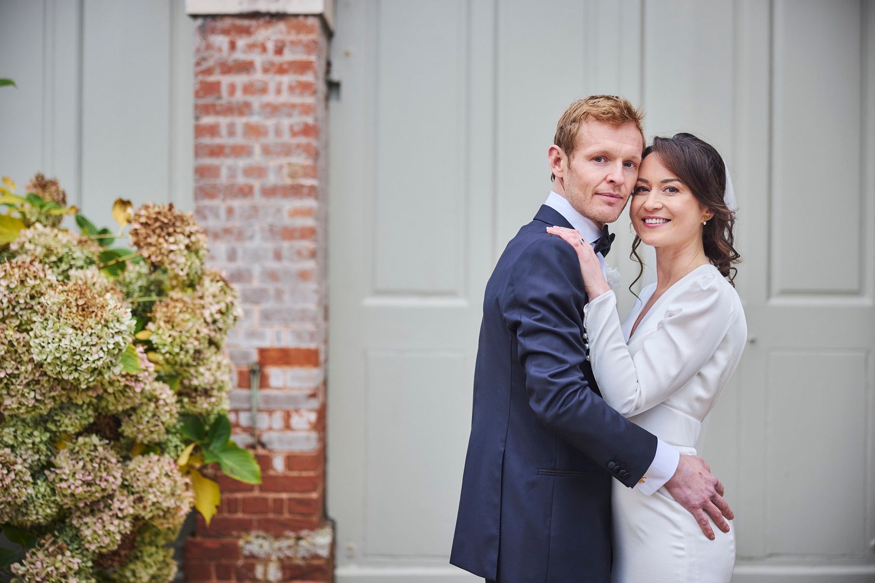 a black and white photo of a bride and groom walking in a field .