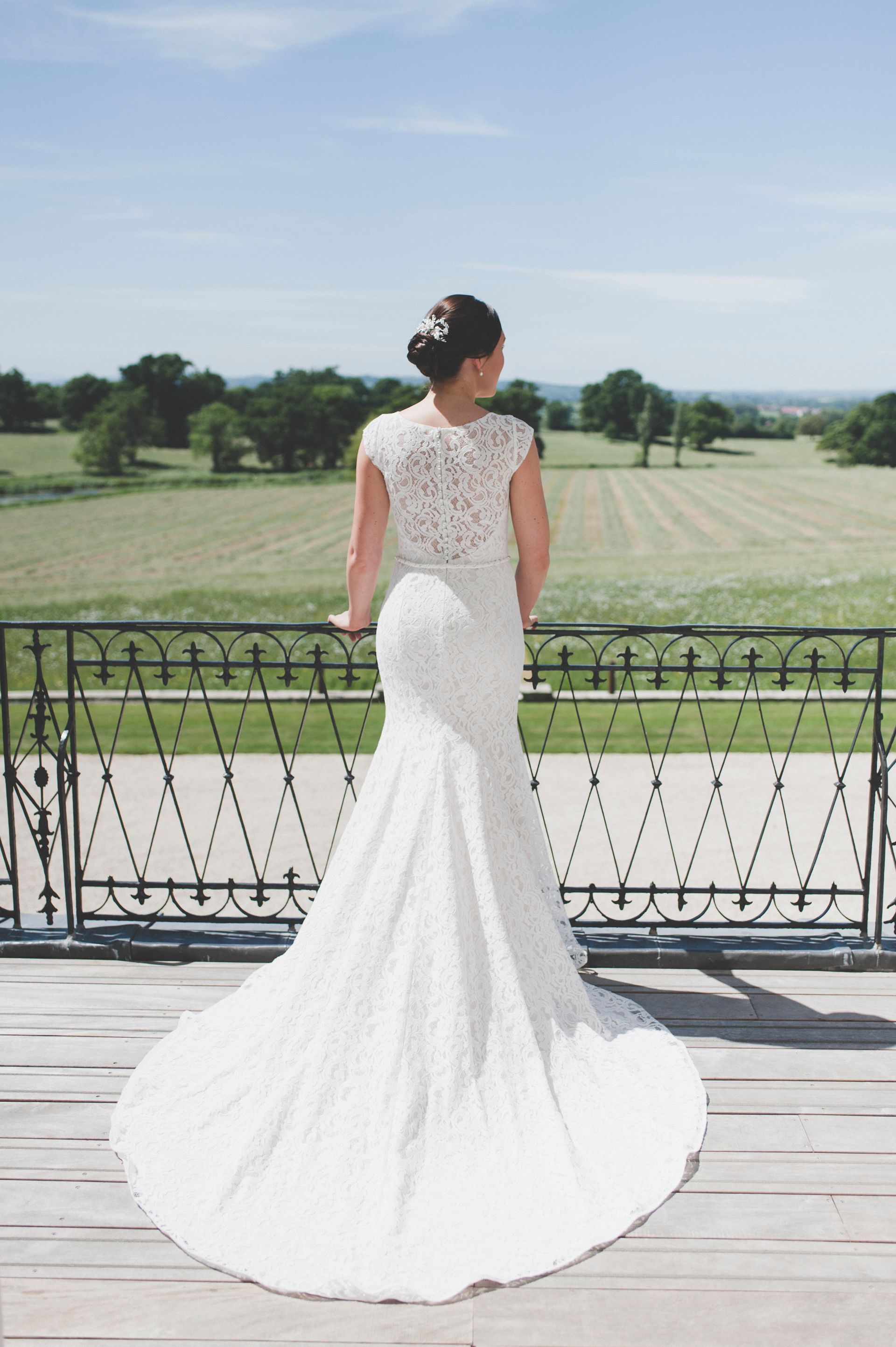 a woman in a wedding dress is standing on a balcony overlooking a field .