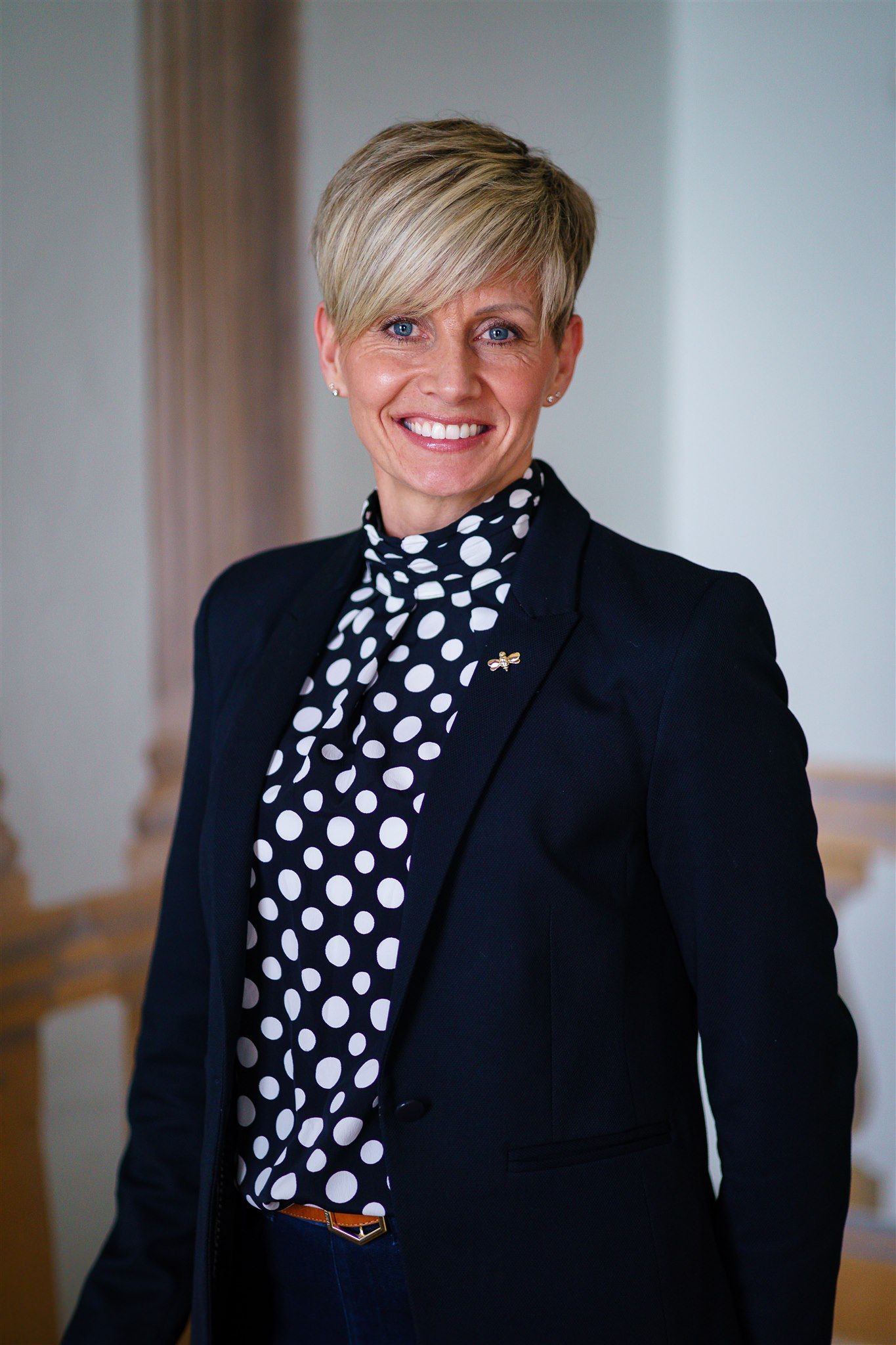 a woman in a white shirt and blue pants is standing in front of a bush .