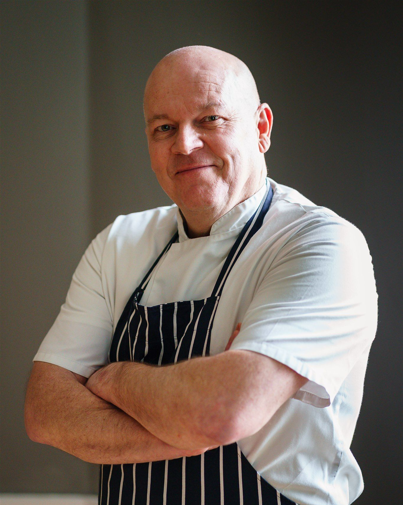 a man in an apron is pouring something into a bowl in a kitchen .