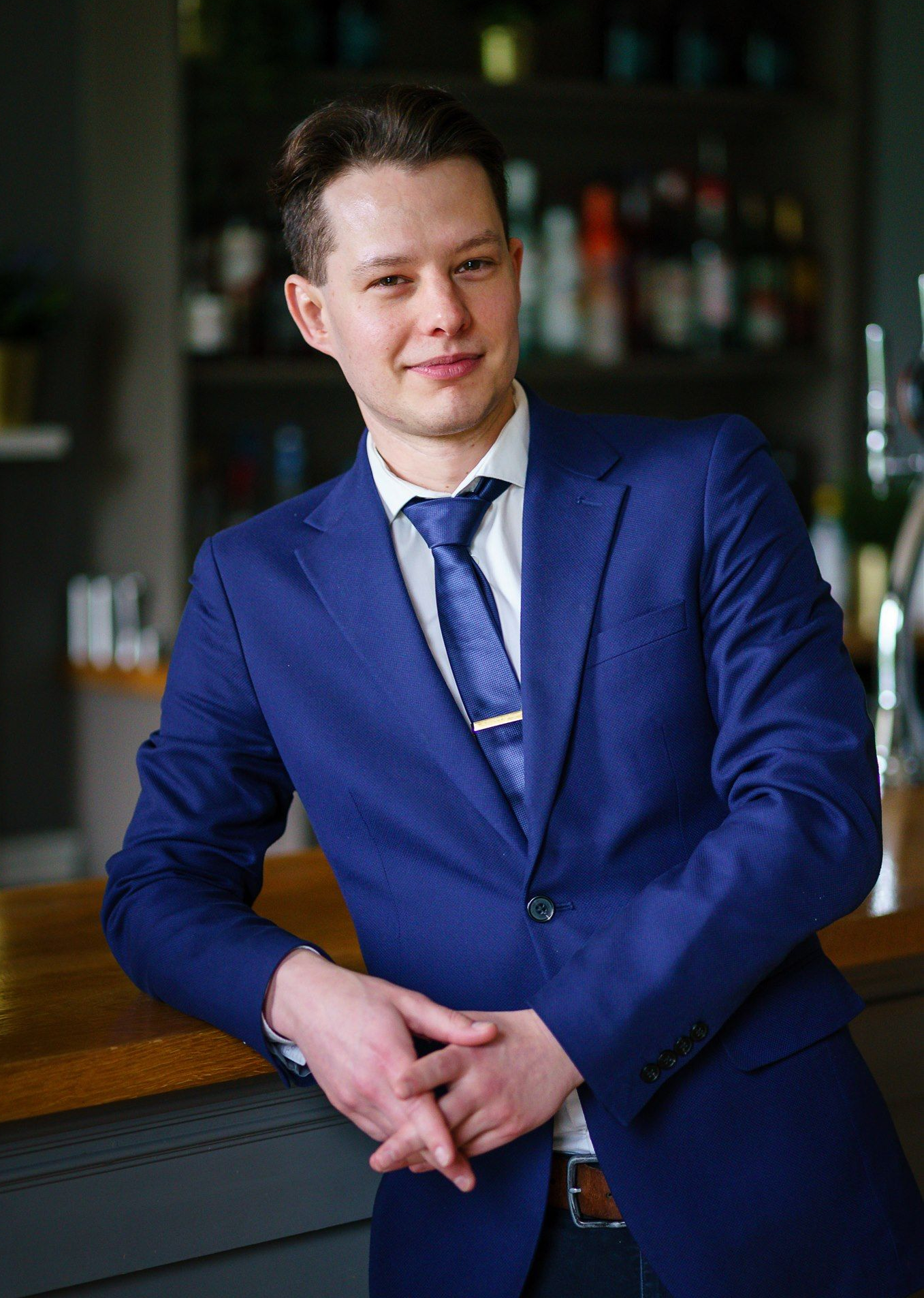 a man in a vest and tie is standing next to a pool table .