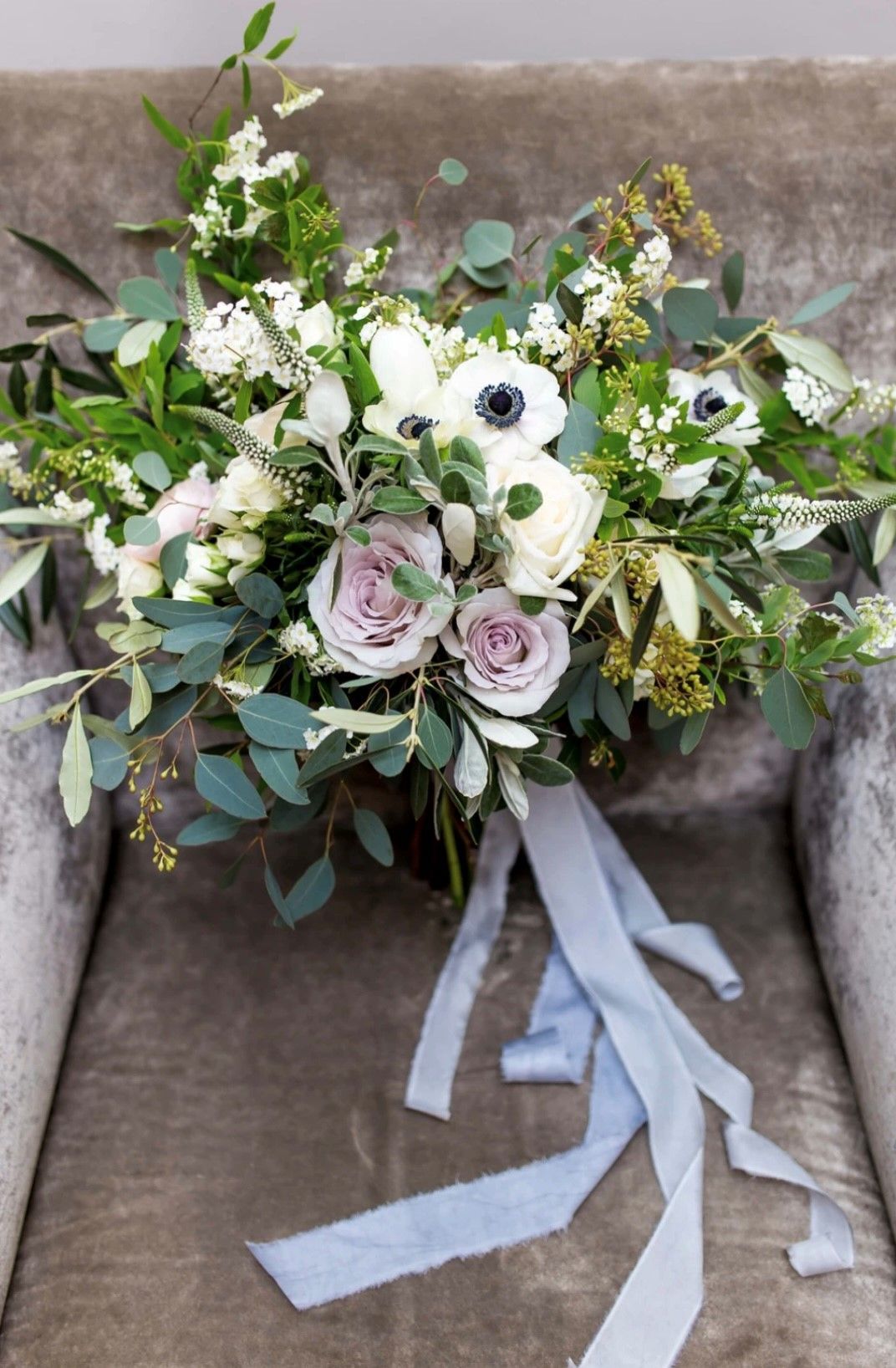 a bouquet of flowers is sitting on a chair with blue ribbons .