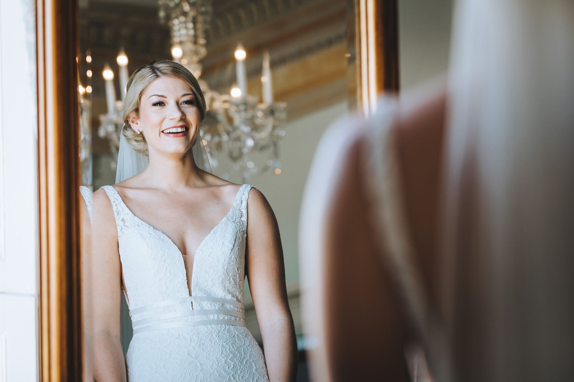 a woman in a wedding dress is looking at herself in a mirror .