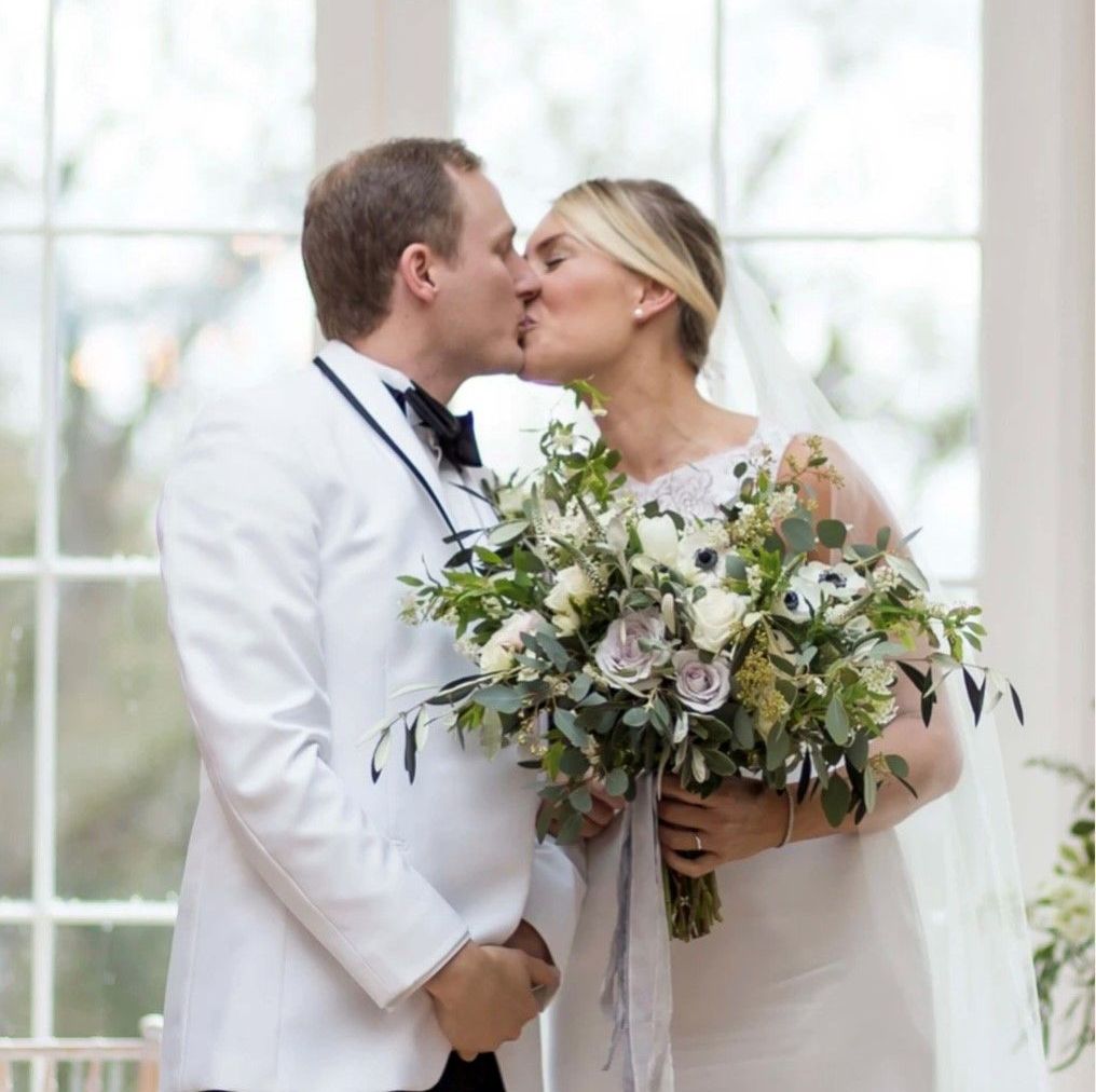 a bride and groom kissing while holding a bouquet of flowers