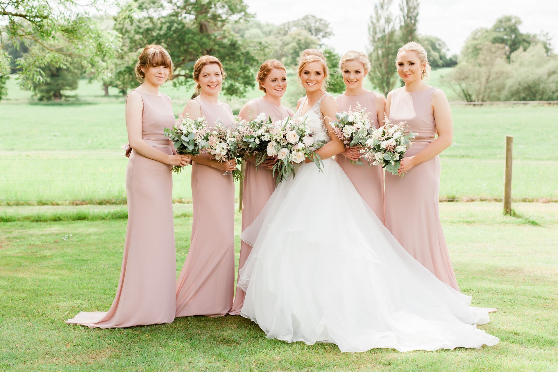 a bride and her bridesmaids are posing for a picture in a field.