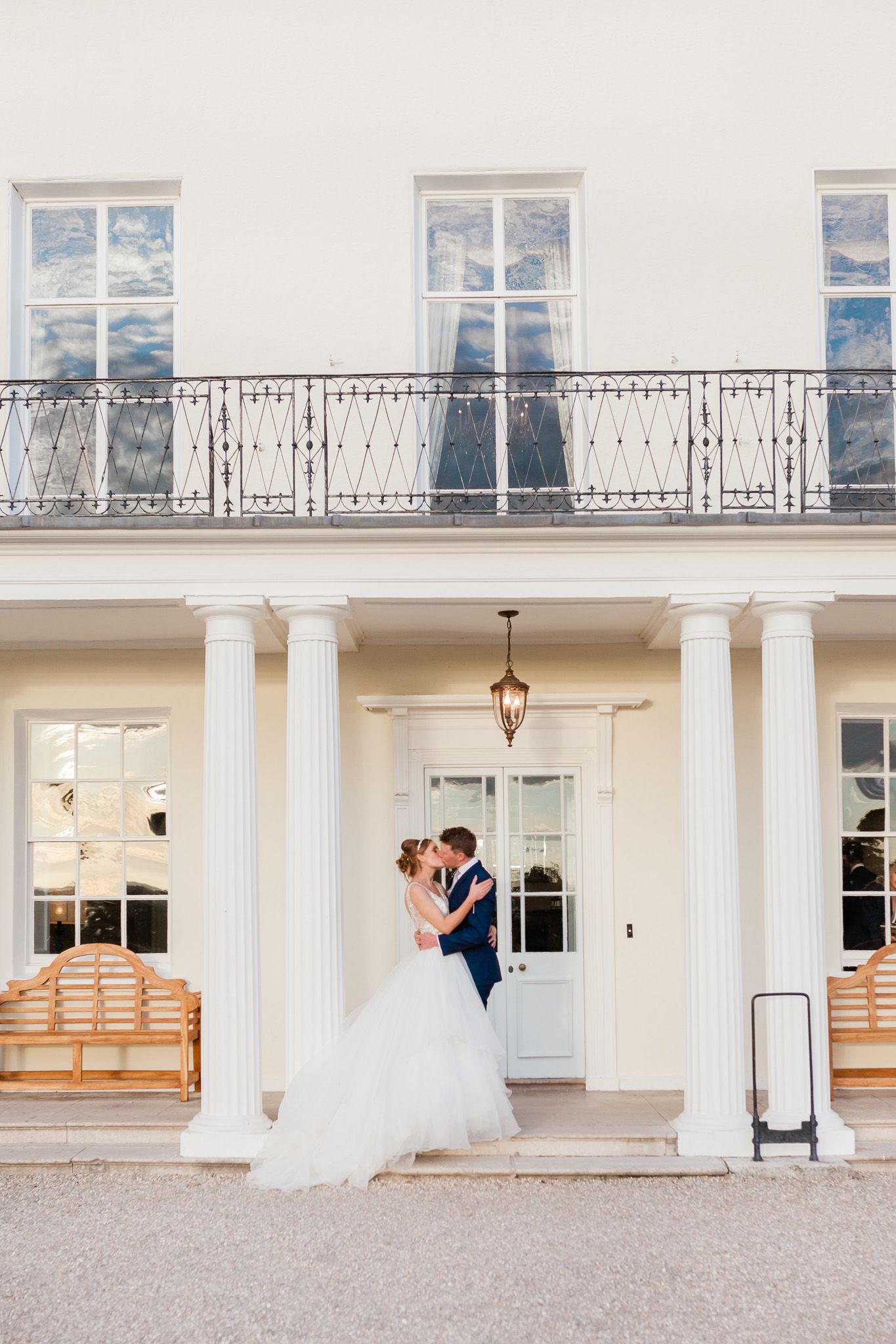 a bride and groom are kissing in front of a white building.