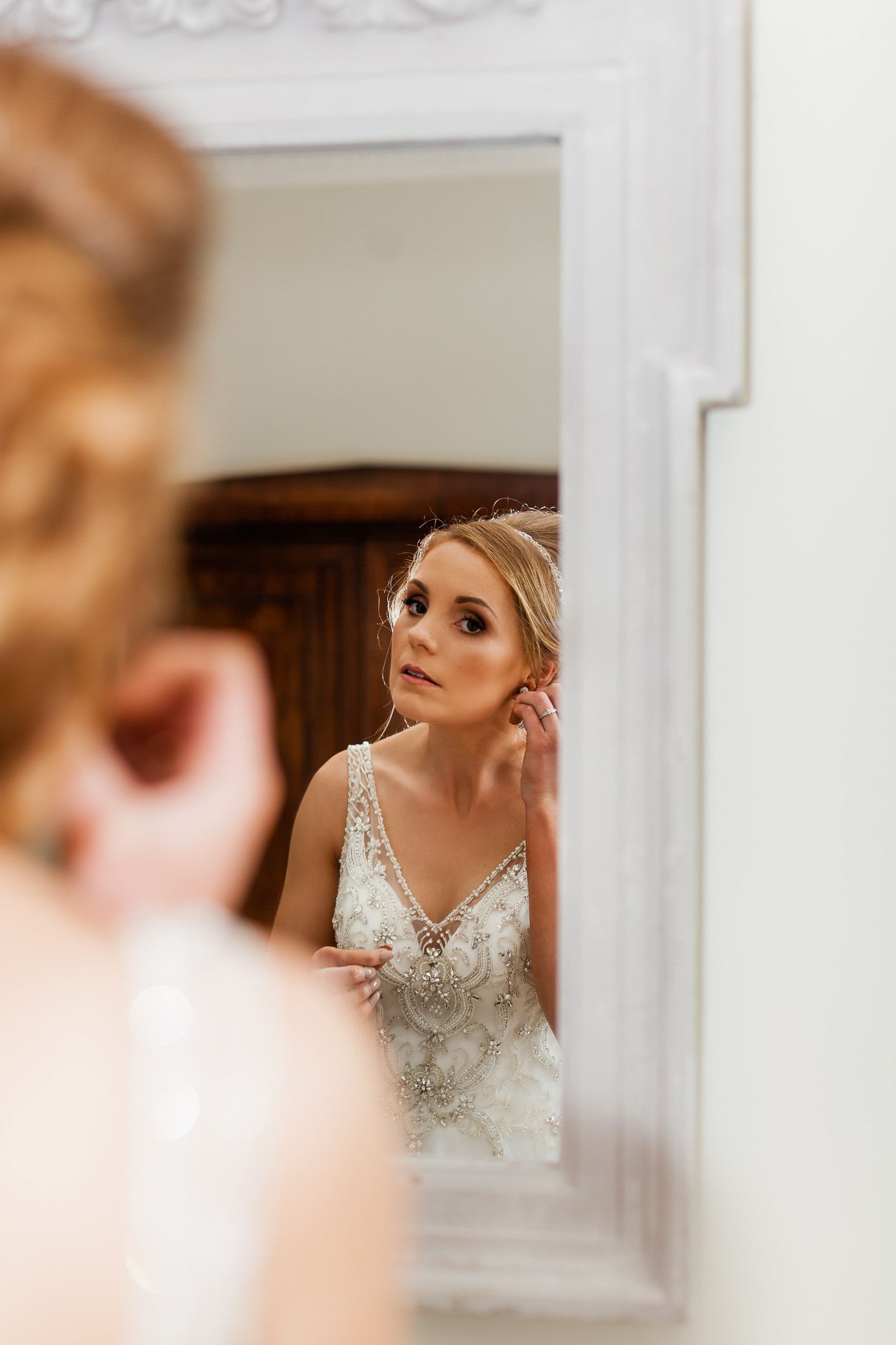 a woman in a wedding dress is looking at herself in a mirror.