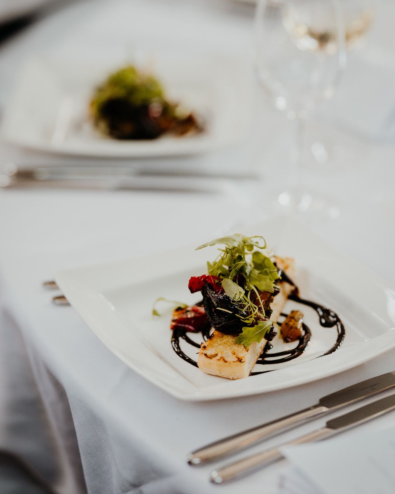 a plate of food on a table with utensils and a glass of wine