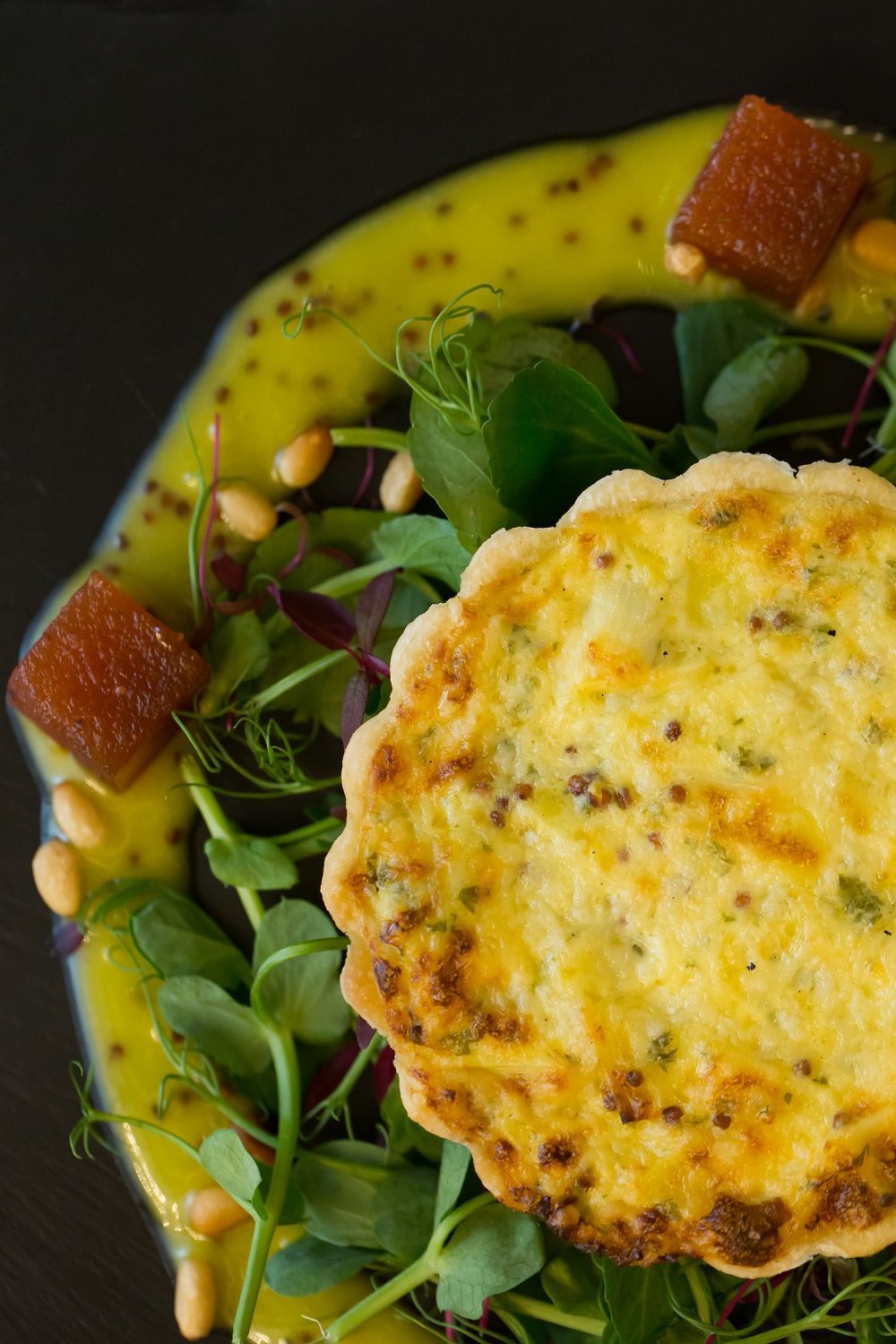 a close up of a quiche on a plate with a salad .
