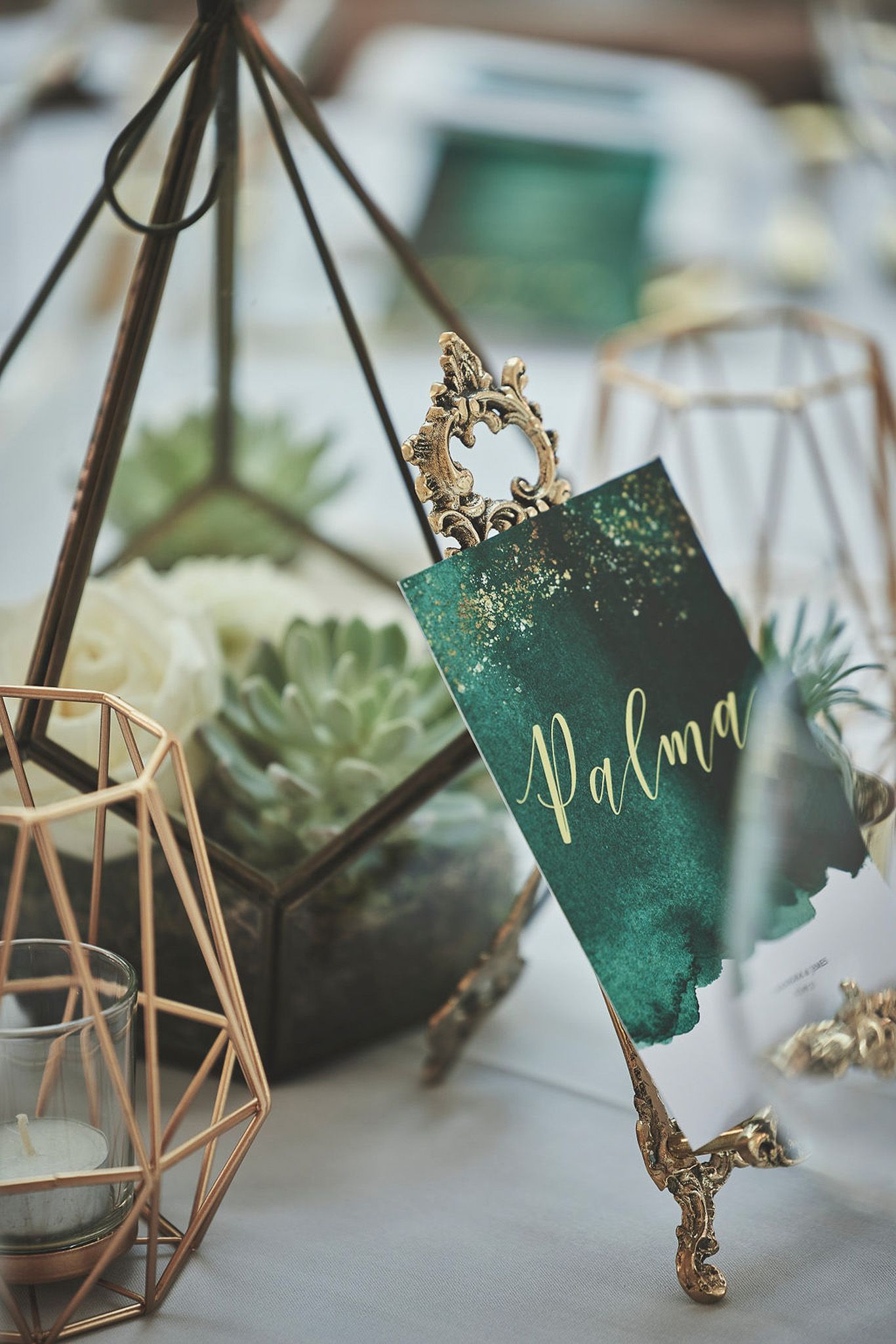 a green place card is sitting on a table next to a candle holder .