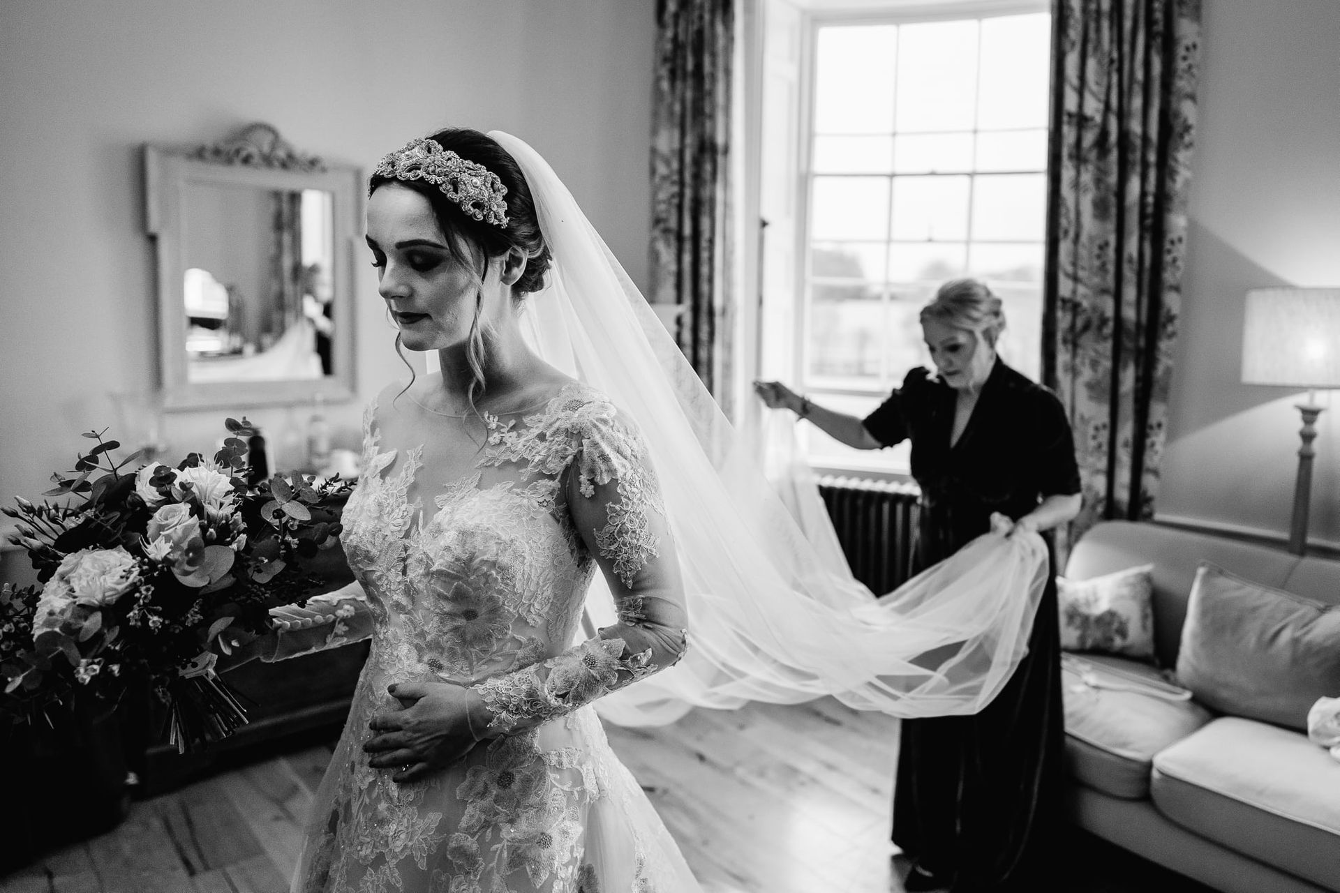 a black and white photo of a bride getting ready for her wedding .