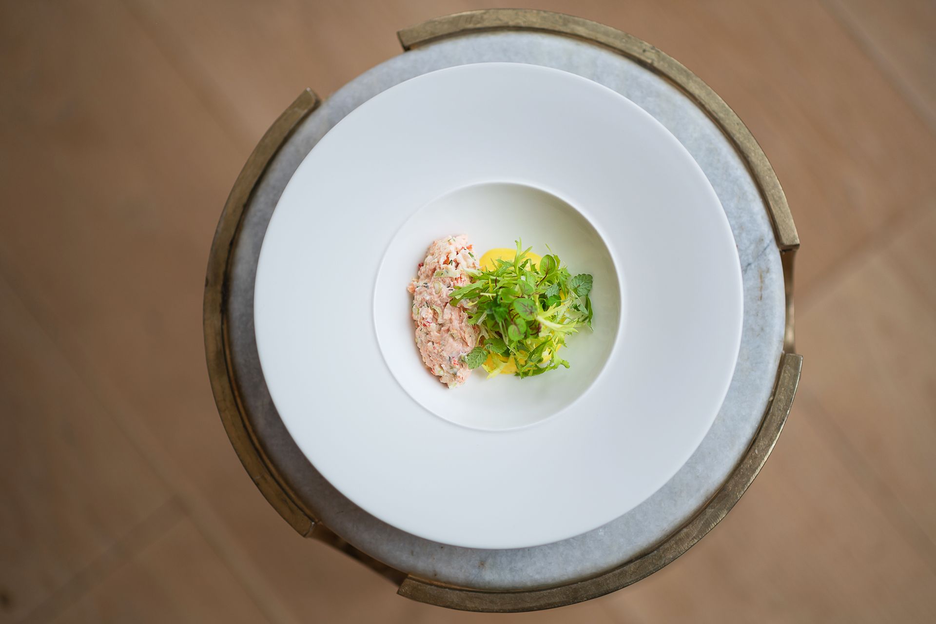 a white plate topped with a bowl of food on a table .