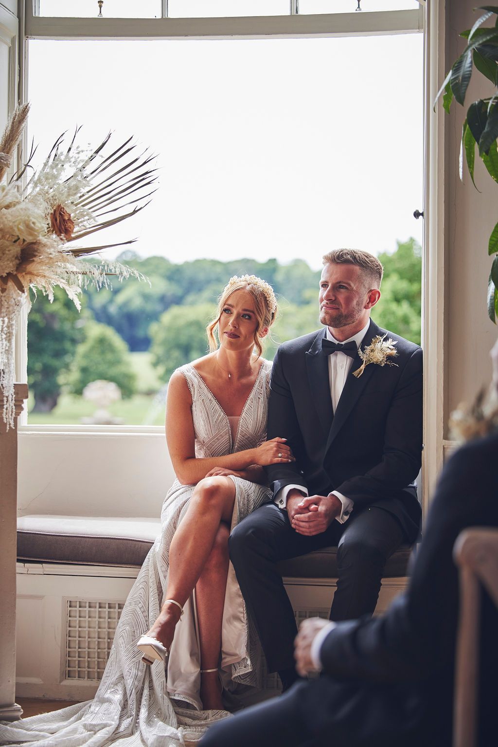 a bride and groom are sitting on a window sill during their wedding ceremony .