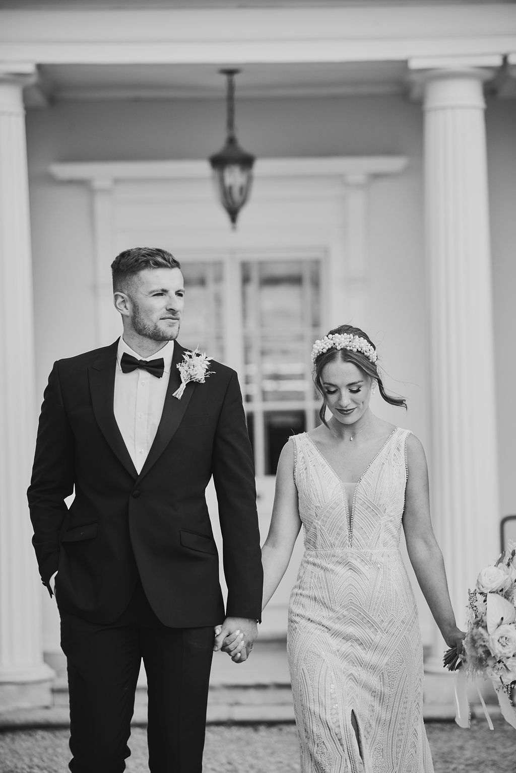 a black and white photo of a bride and groom holding hands .