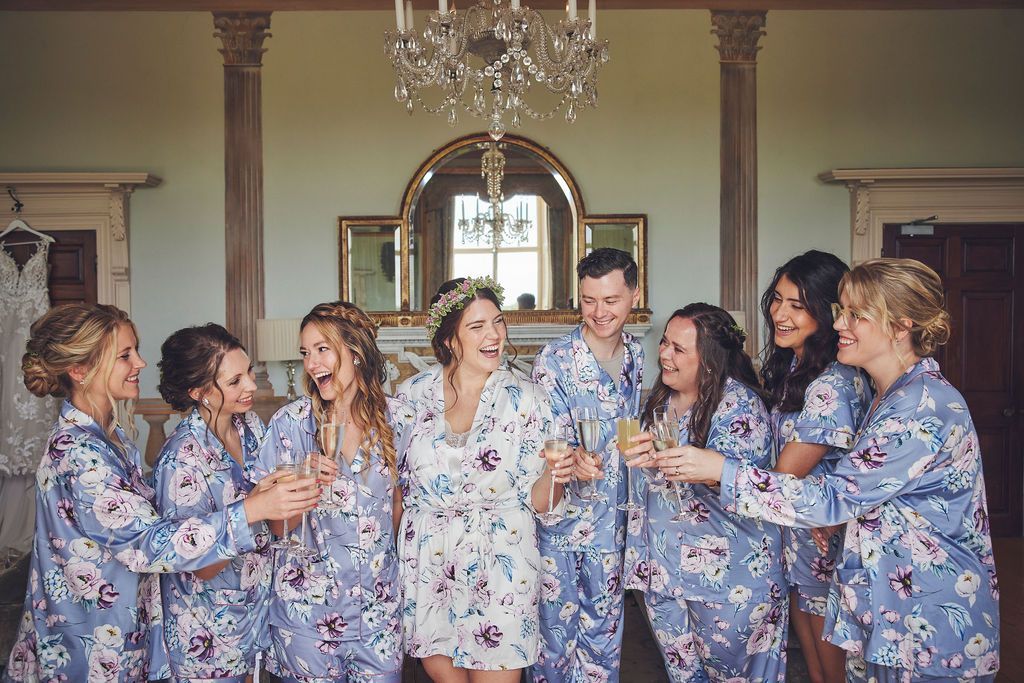 a bride and her bridesmaids are toasting with champagne in a room .