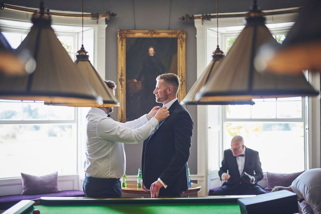 a man in a suit is getting ready in front of a pool table .