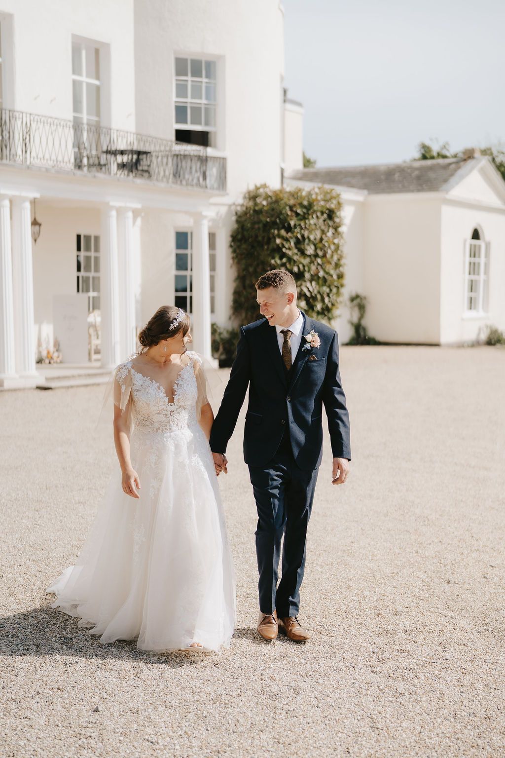 a bride and groom are posing for a picture in front of a large white building .
