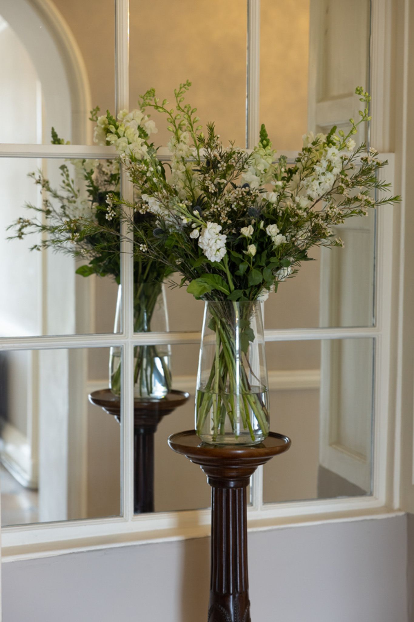 two vases of flowers are sitting in front of a mirror