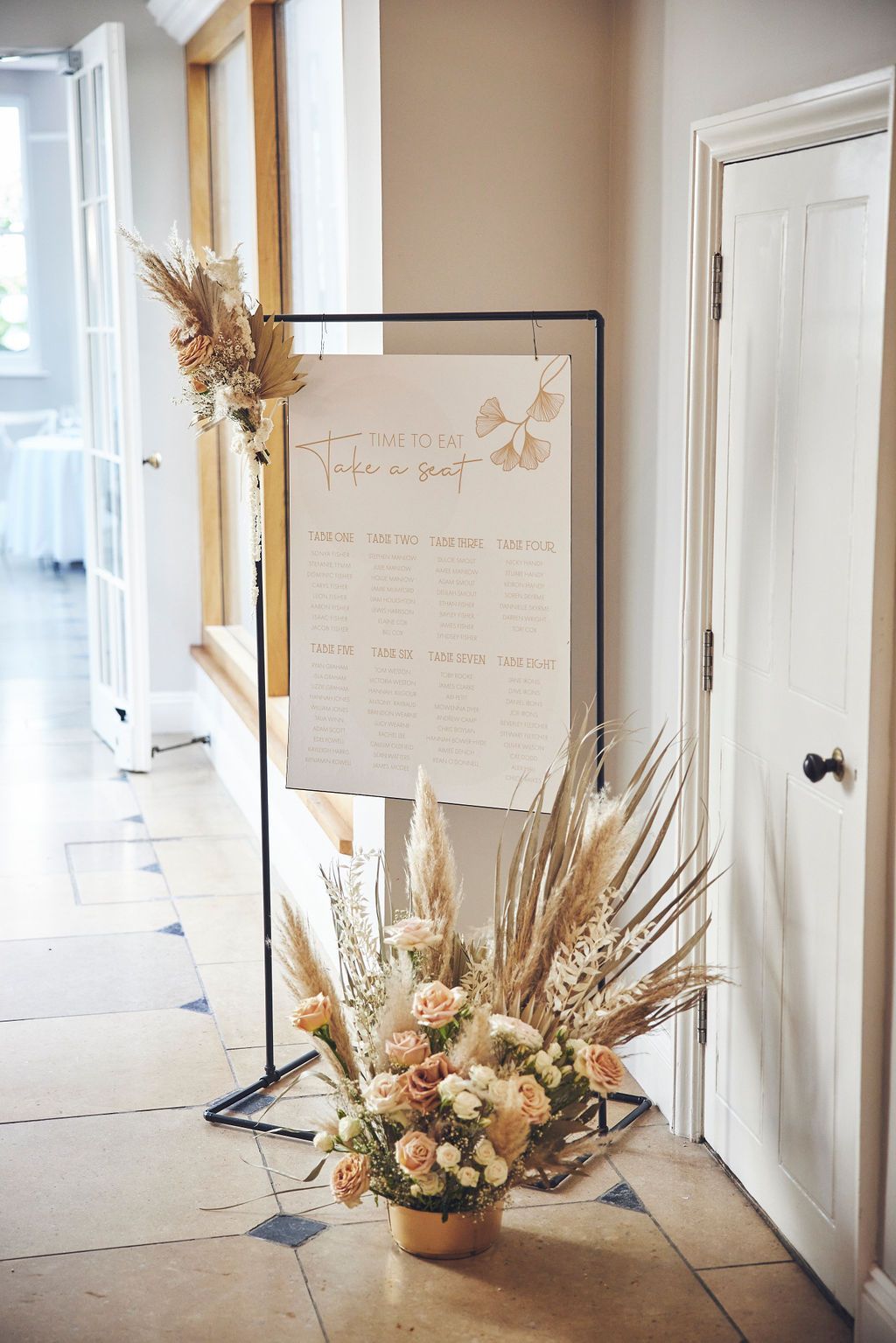 a vase of flowers is sitting next to a sign in a hallway .