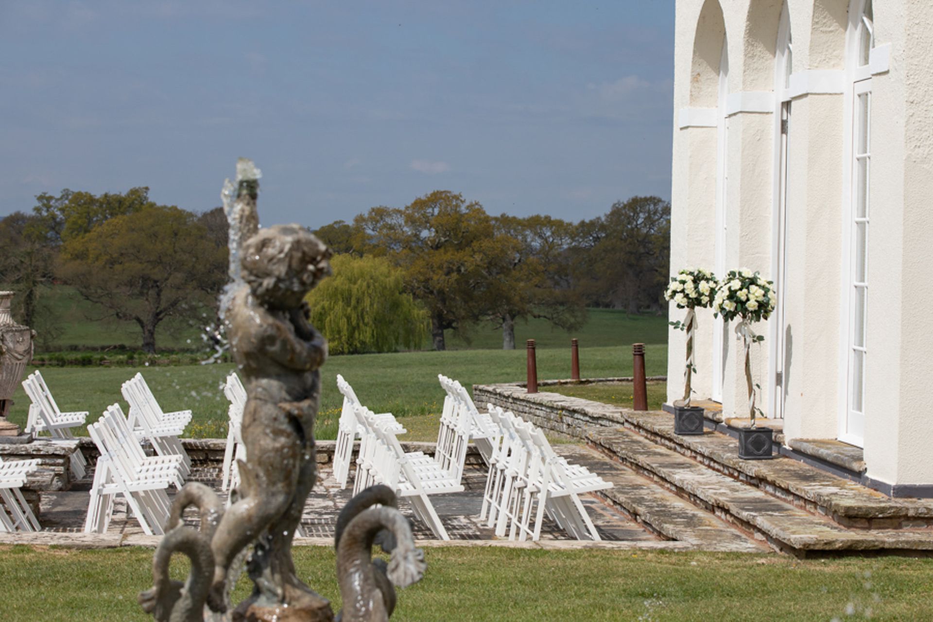 a statue of a woman standing next to a fountain in front of a white building .