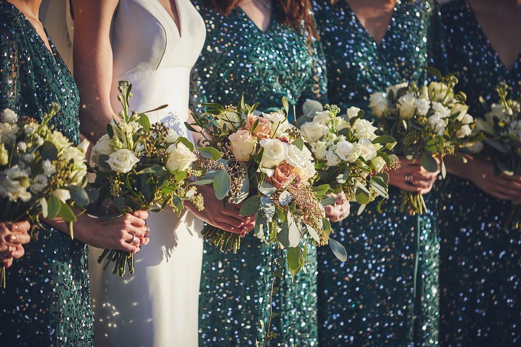 a bride and her bridesmaids are holding bouquets of flowers .