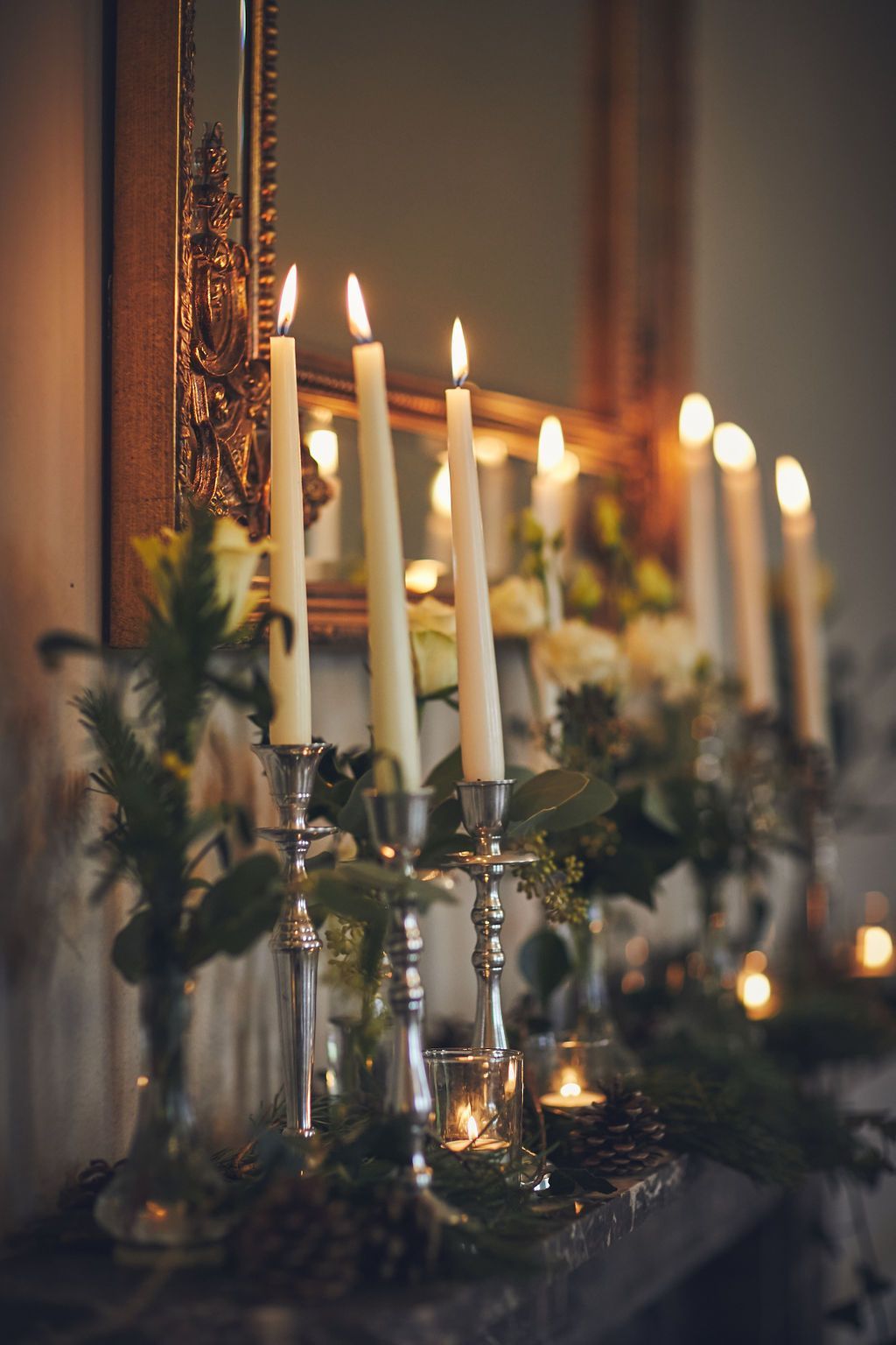 a row of candles are lit on a mantle in front of a mirror .