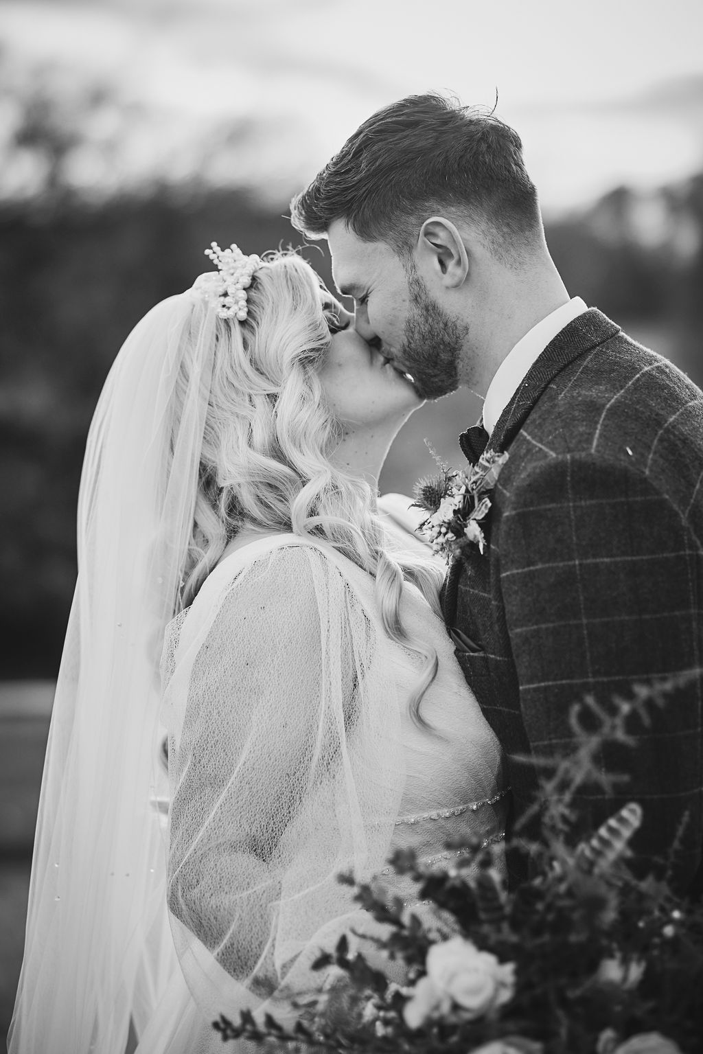 a bride and groom are kissing in a black and white photo .