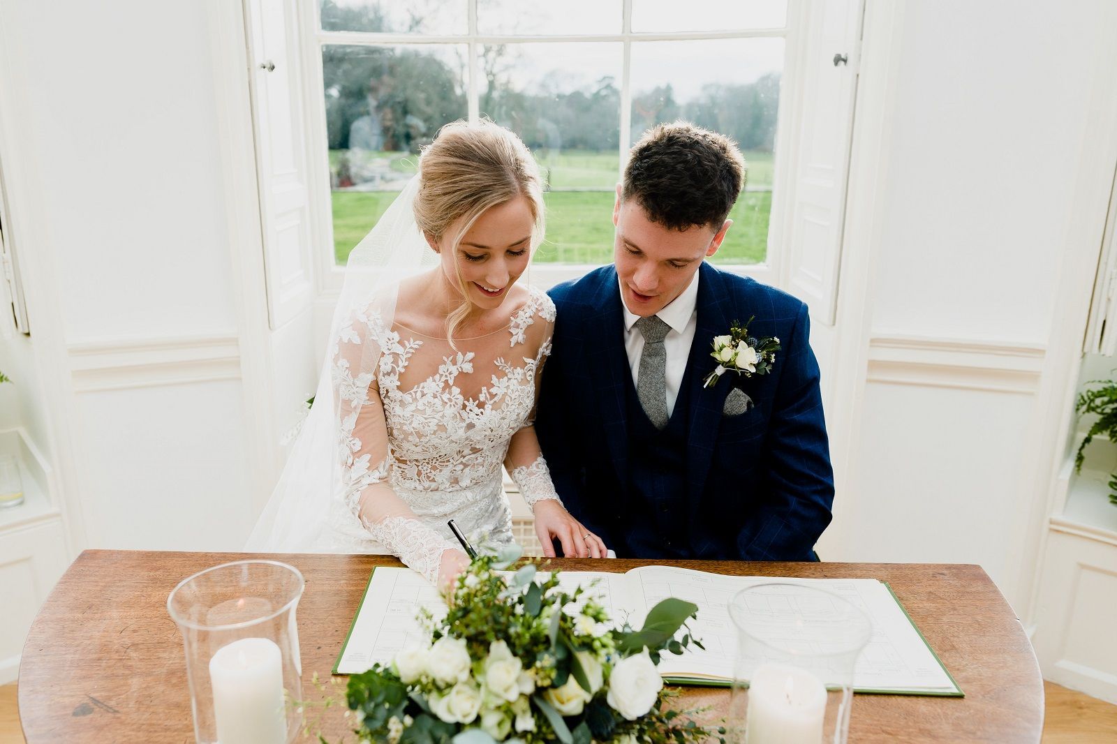 a bride and groom are sitting at a table signing a wedding register .