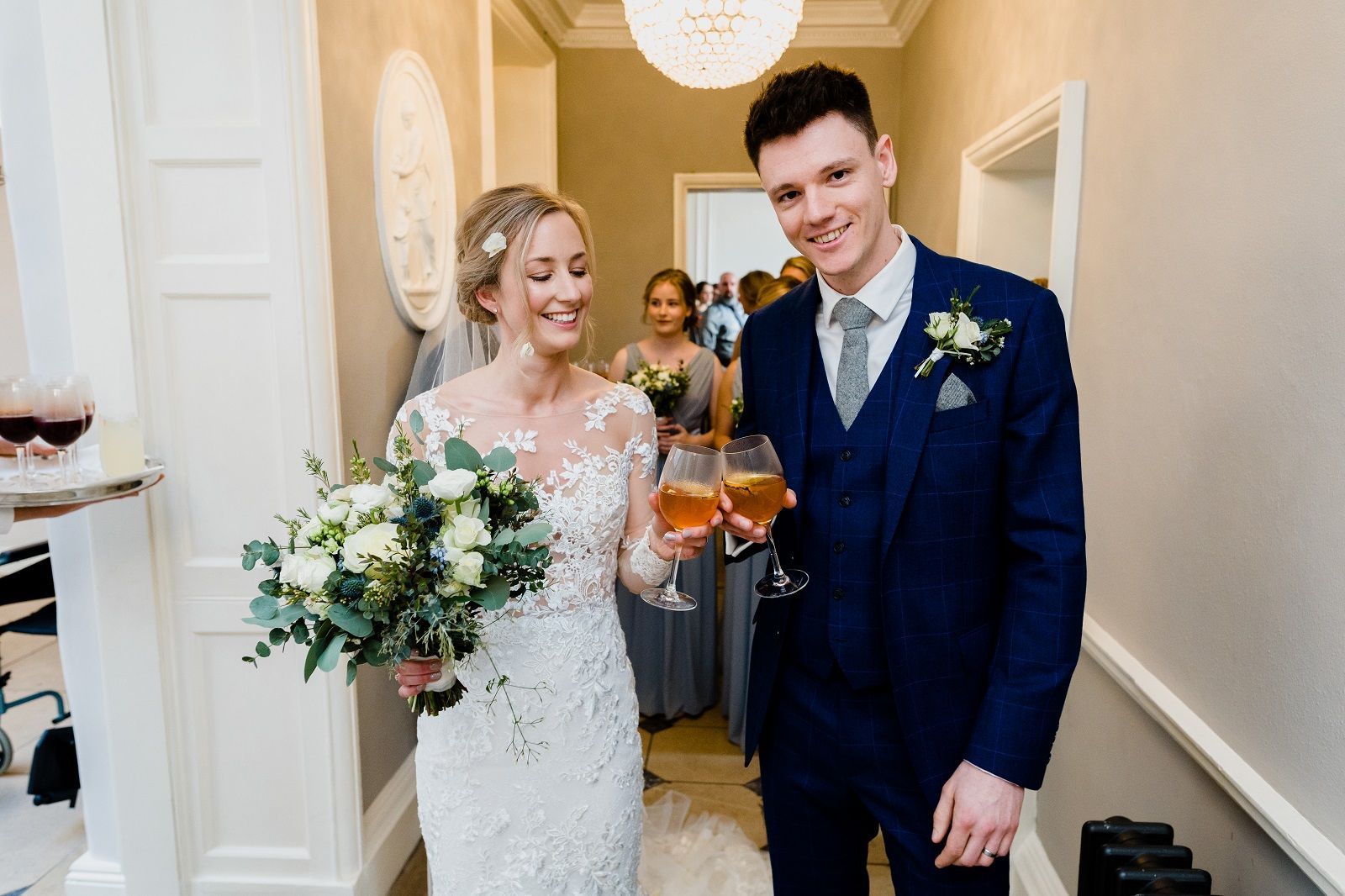 a bride and groom are holding wine glasses in a hallway .