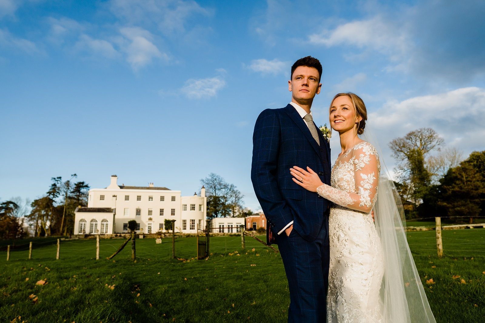 a bride and groom are posing for a picture in front of a large white building .