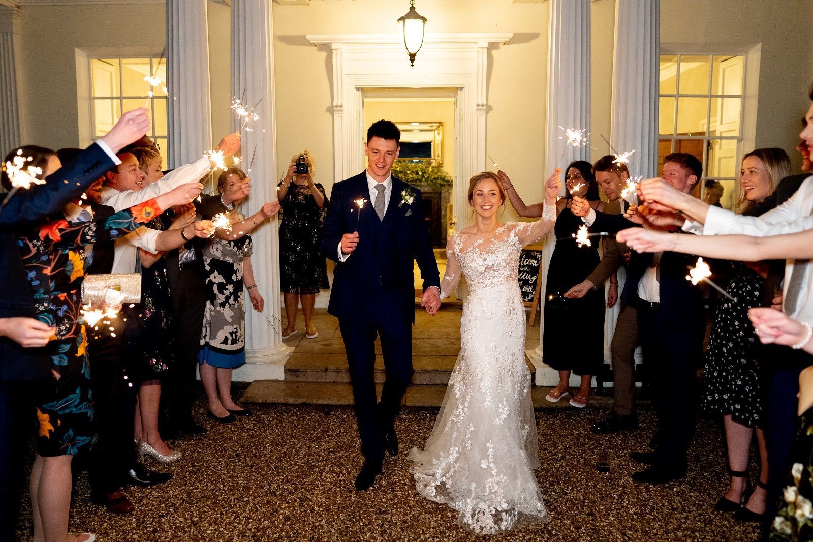 a bride and groom are walking through a tunnel of sparklers .