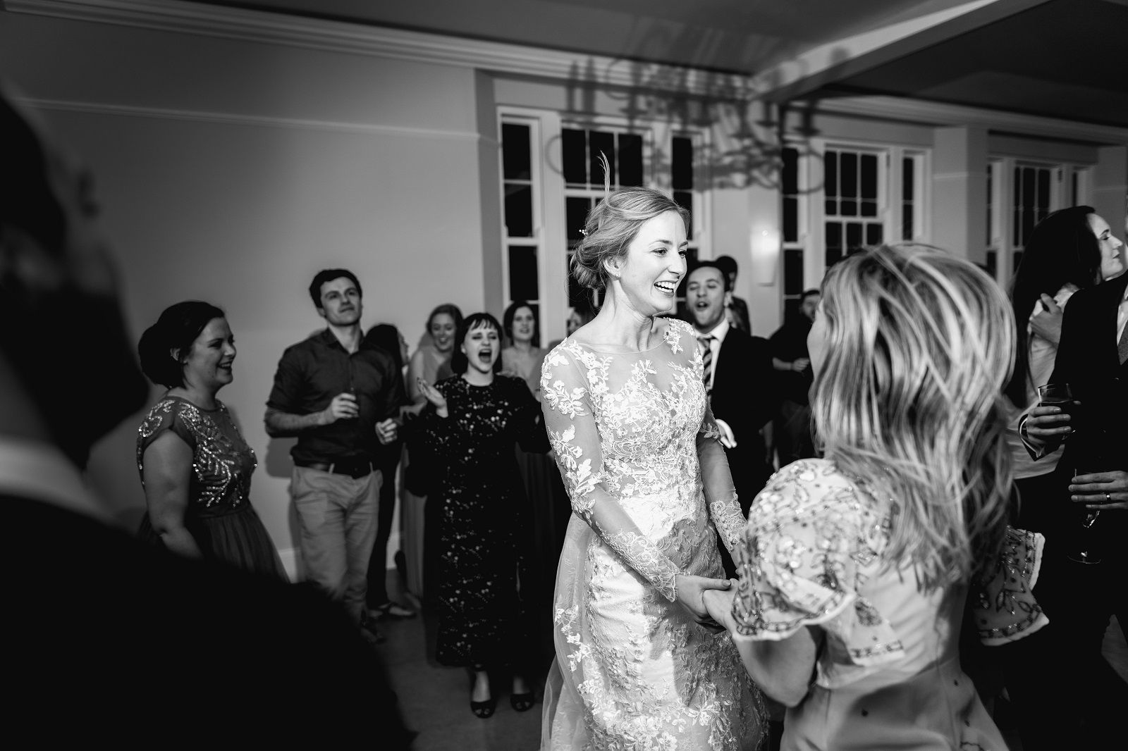 a black and white photo of a bride and her mother dancing at a wedding reception .