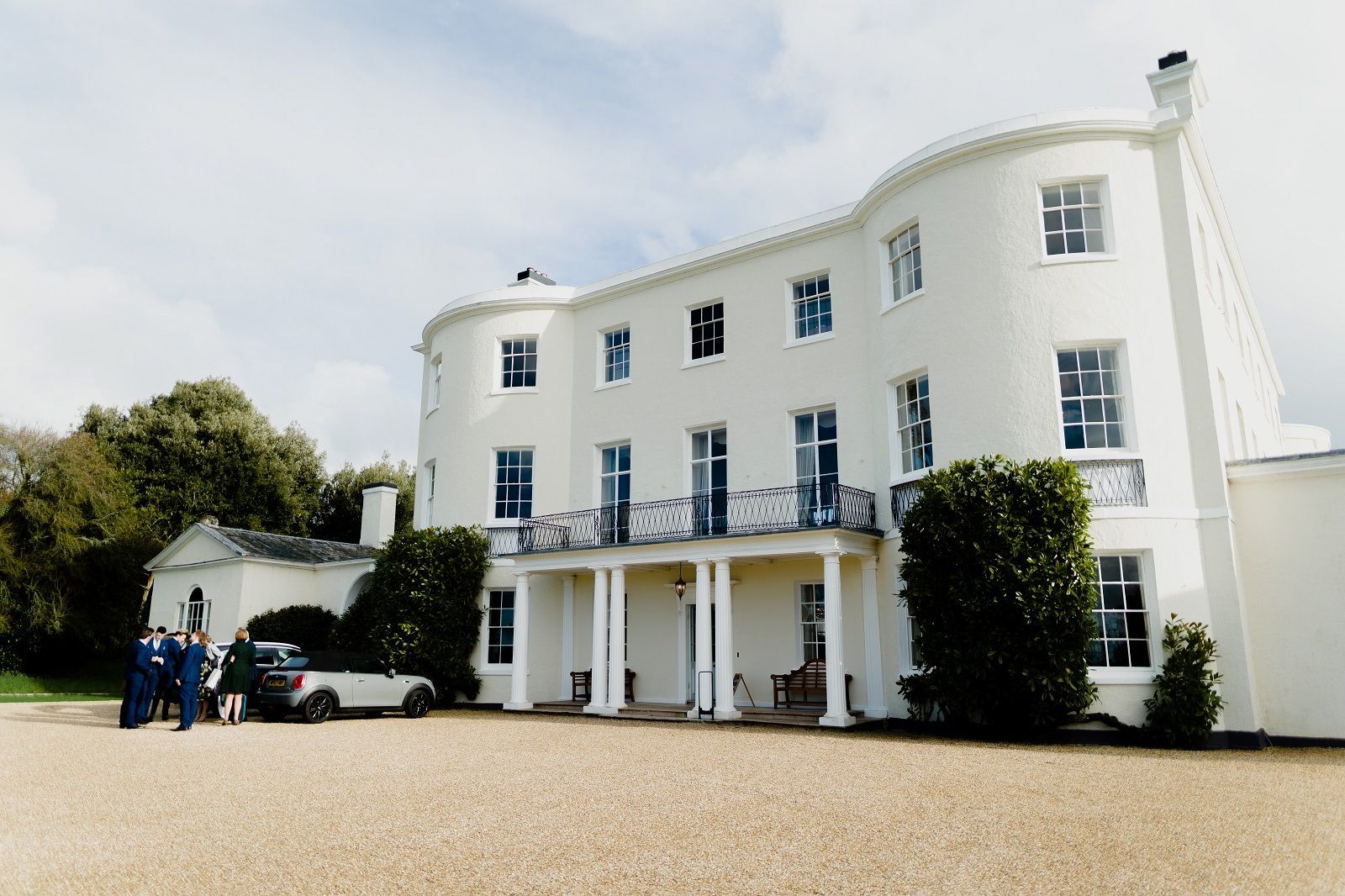 a group of people are standing in front of a large white house .