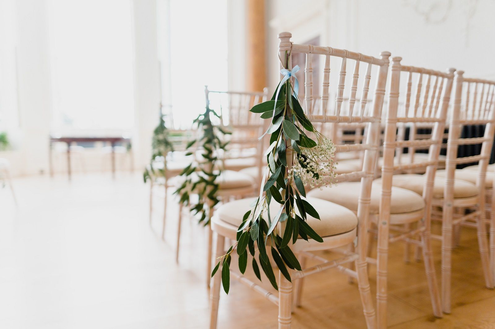 a row of chairs decorated with flowers and greenery for a wedding ceremony .